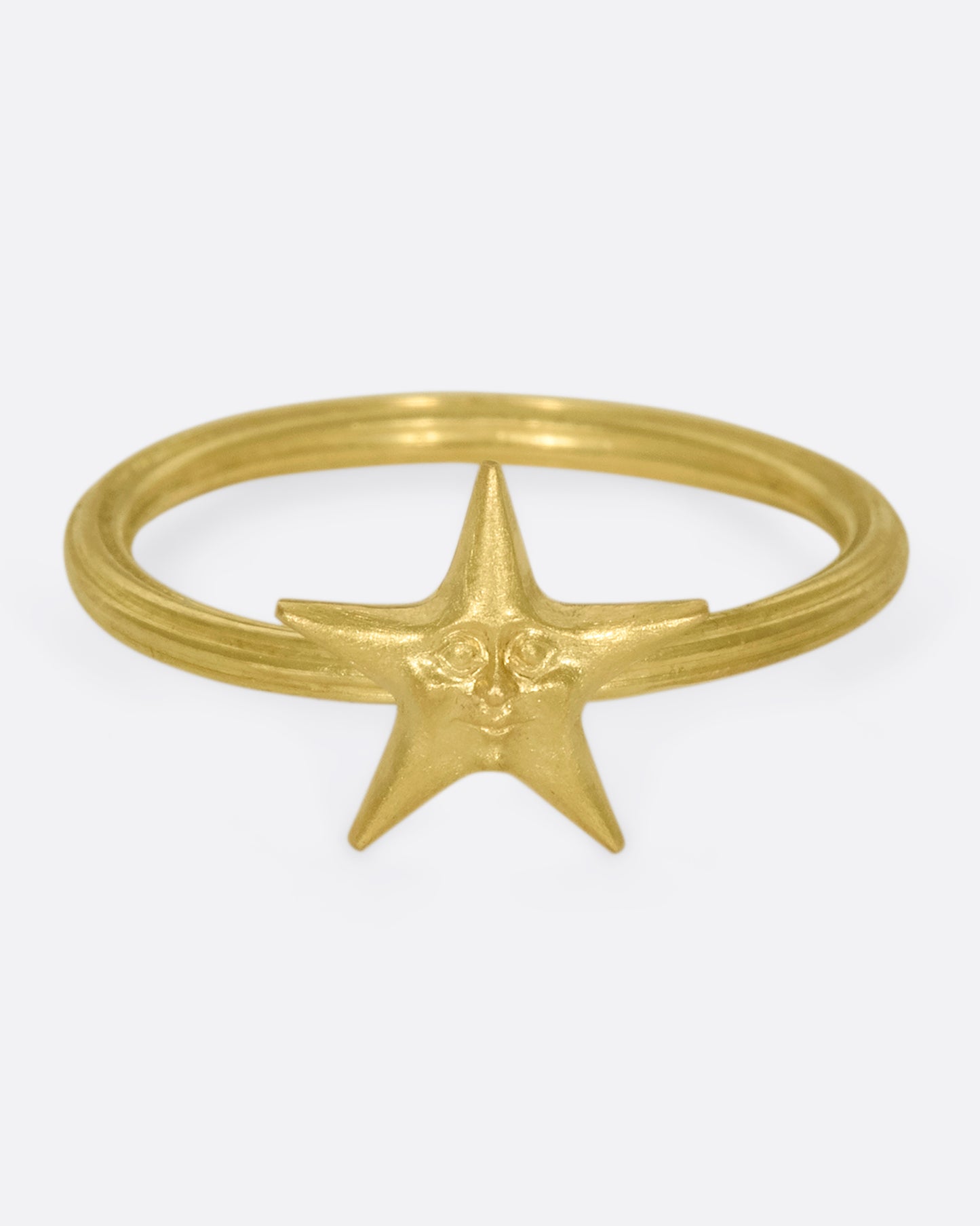 An 18k gold star ring with a sweet face emerging in the center.