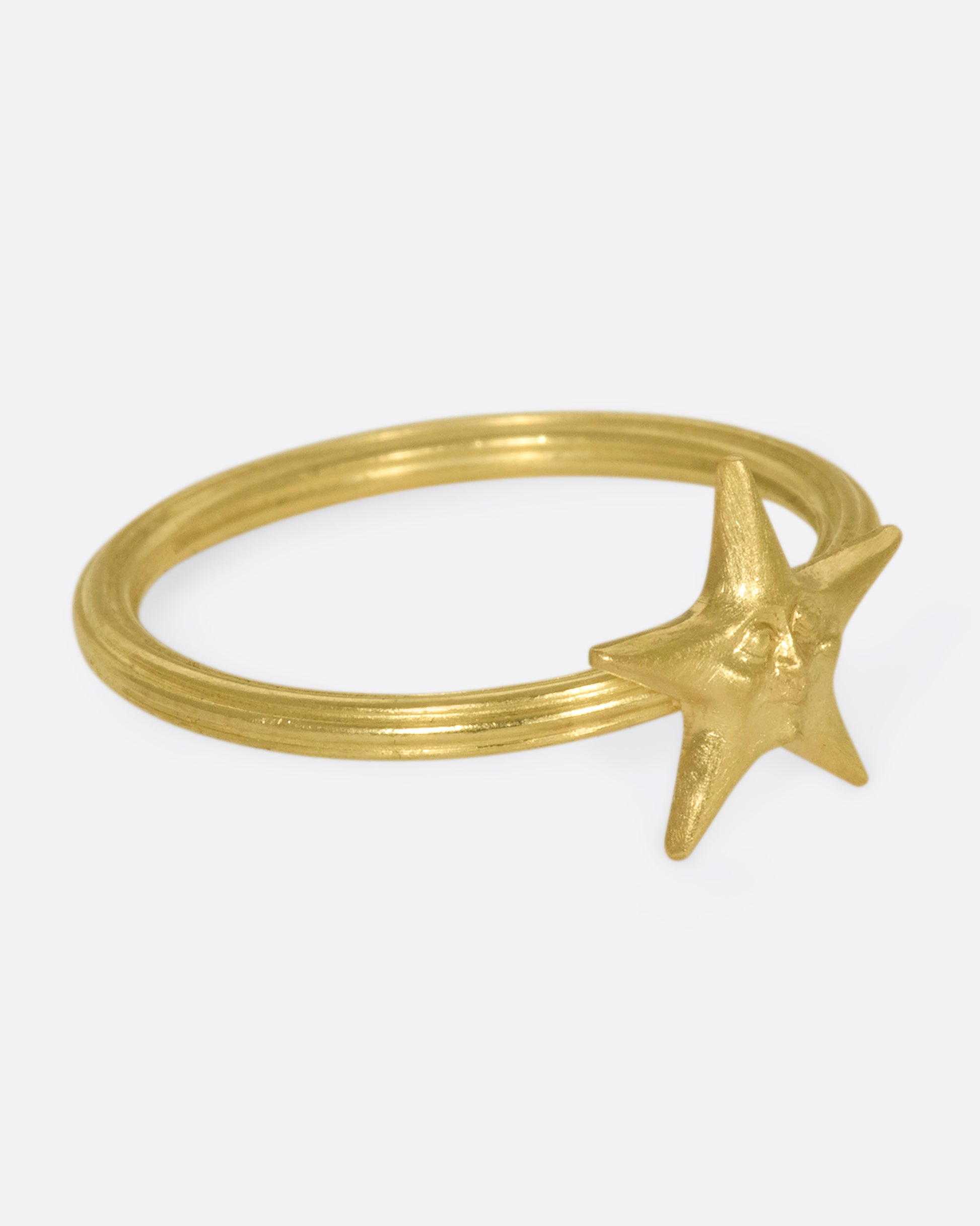 An 18k gold star ring with a sweet face emerging in the center.