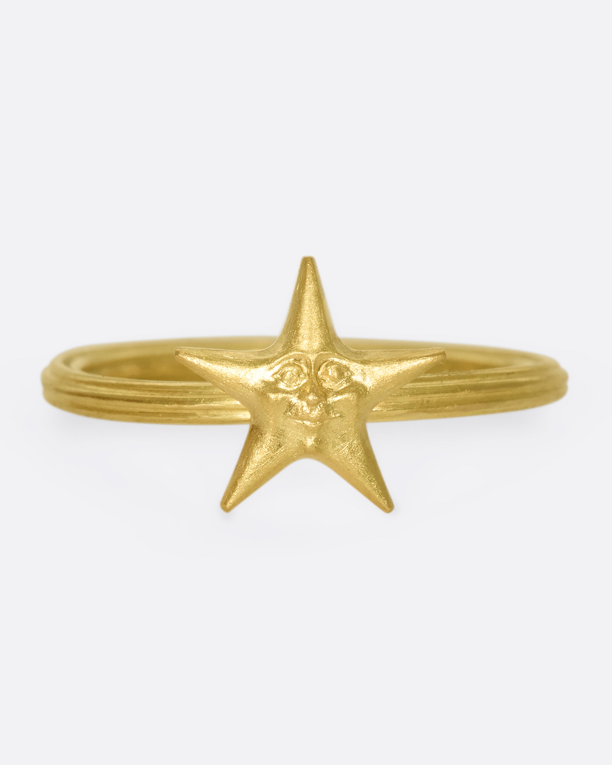 An 18k gold star ring with a sweet face emerging in the center.