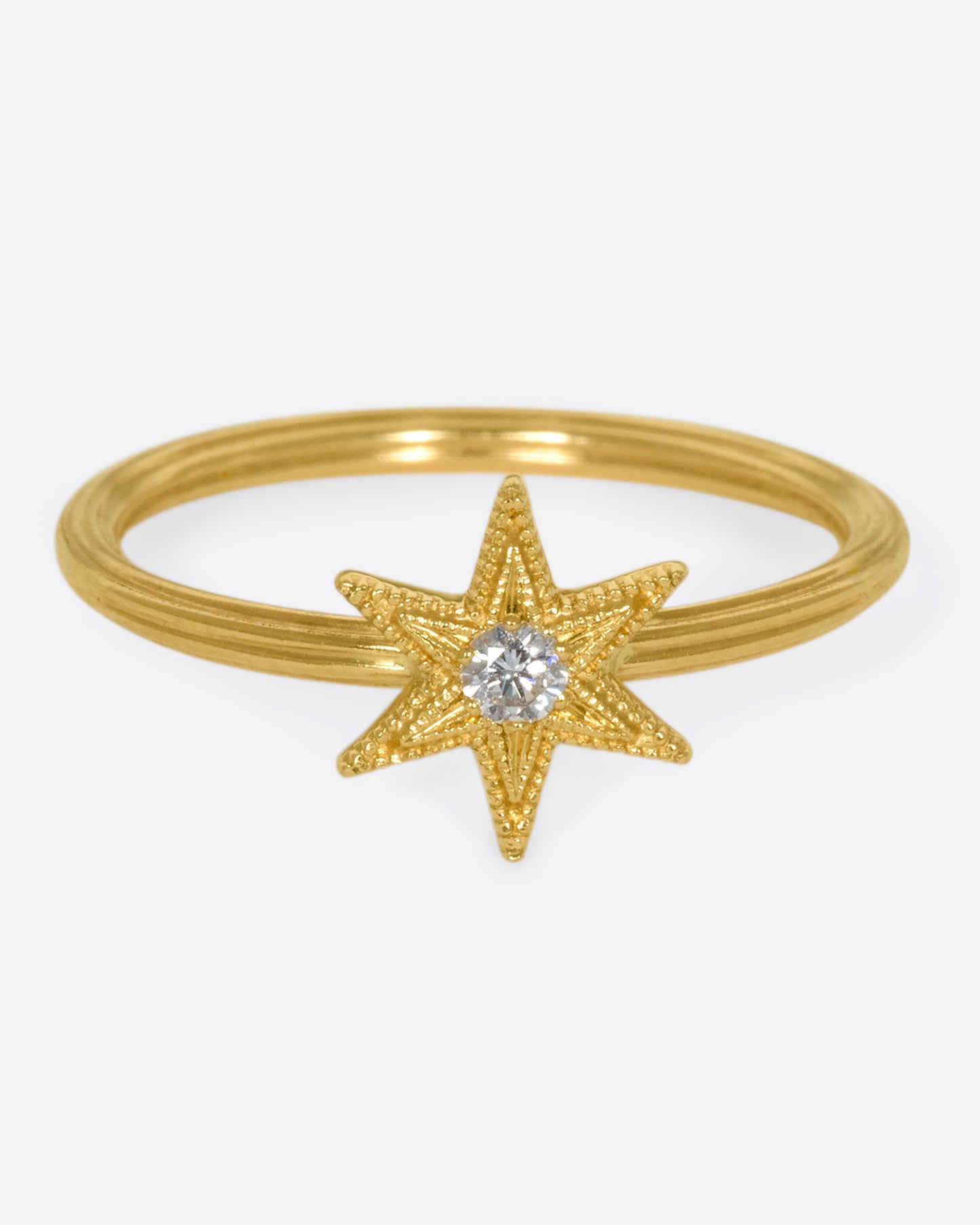 An 18k gold six-point star ring with a round diamond nestled in the center