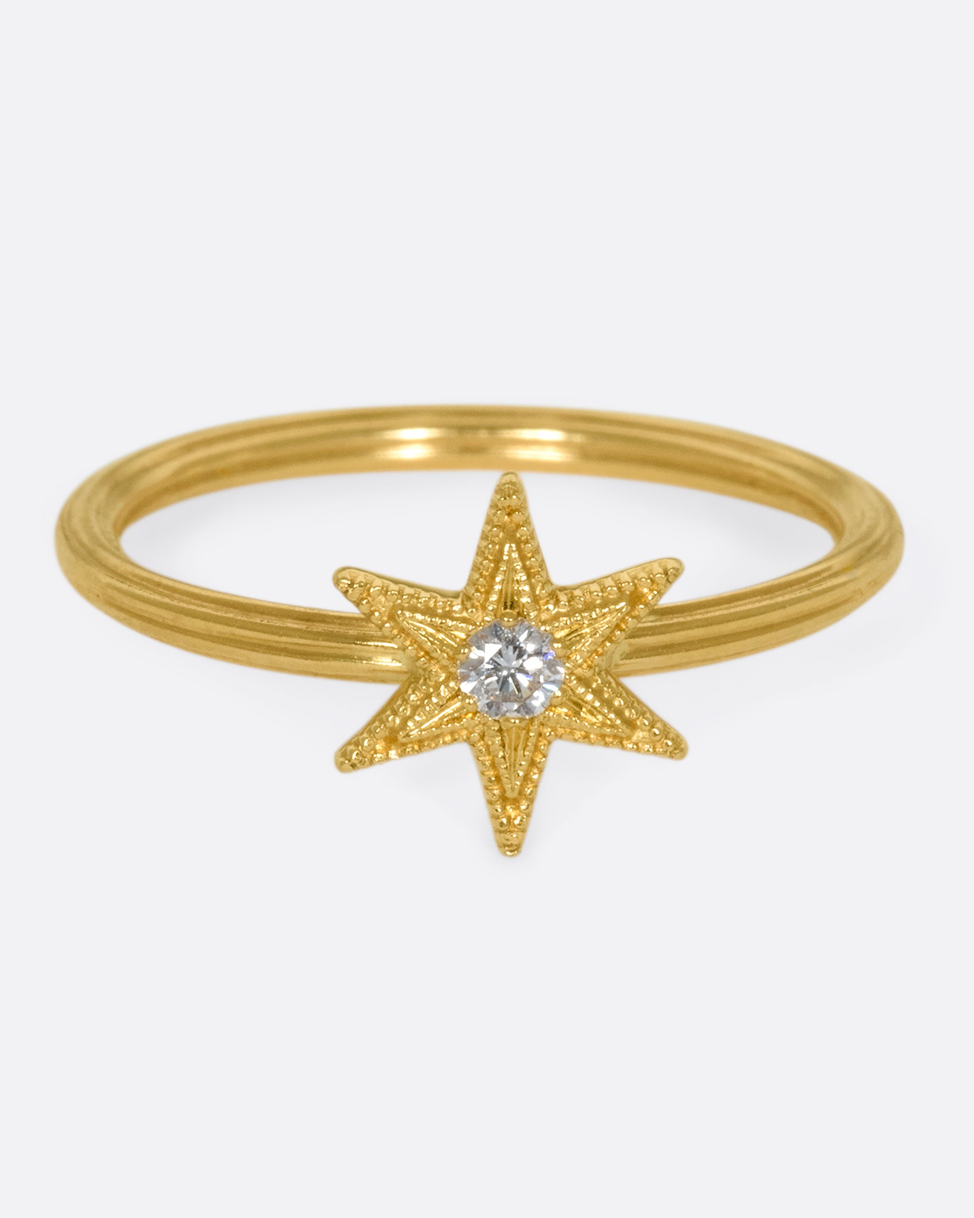 An 18k gold six-point star ring with a round diamond nestled in the center