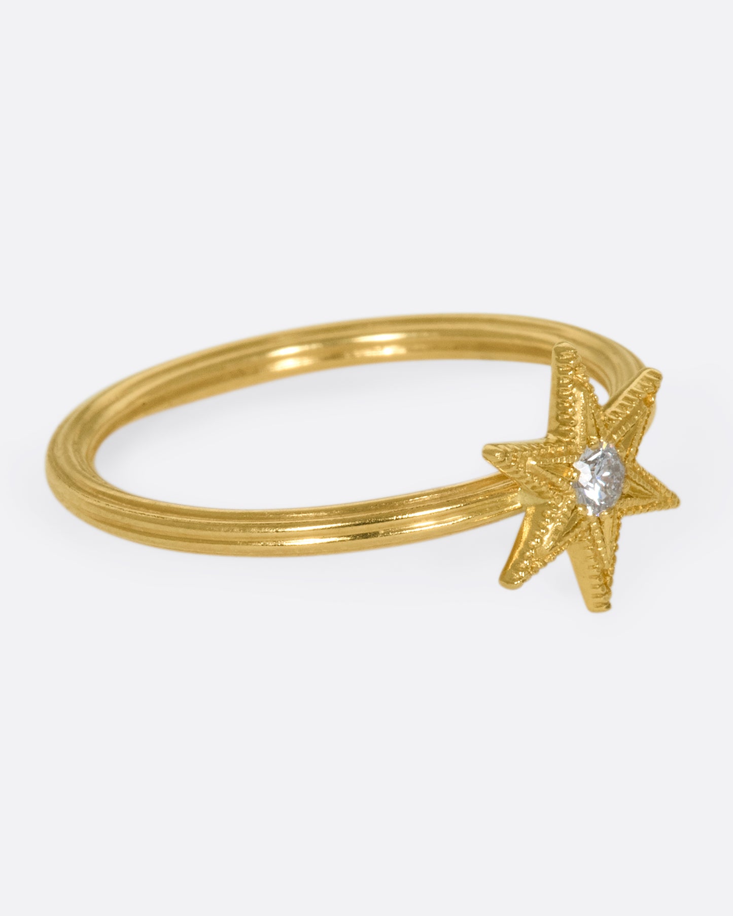 An 18k gold six-point star ring with a round diamond nestled in the center