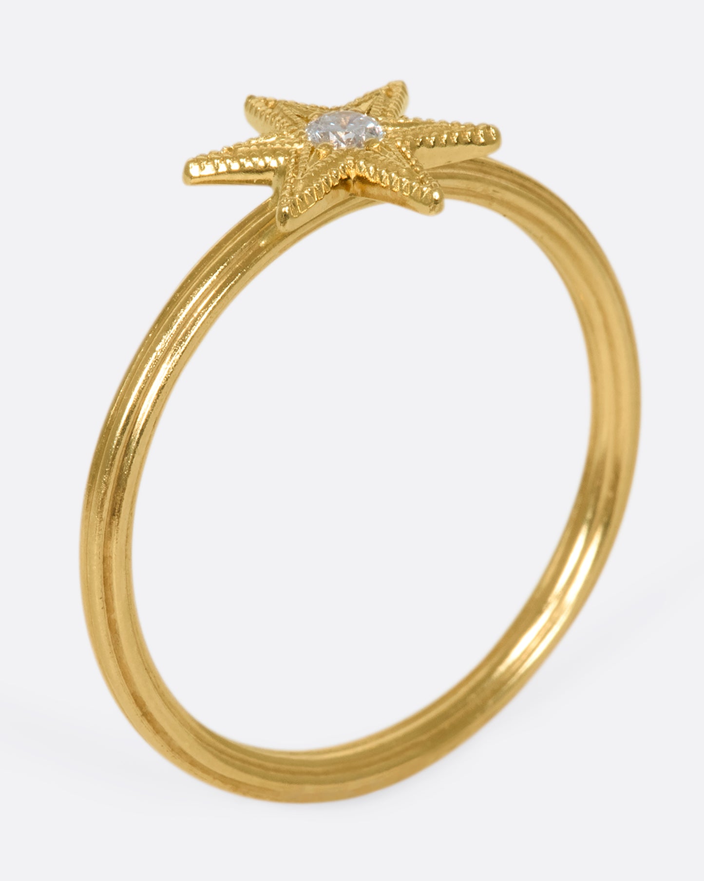 An 18k gold six-point star ring with a round diamond nestled in the center