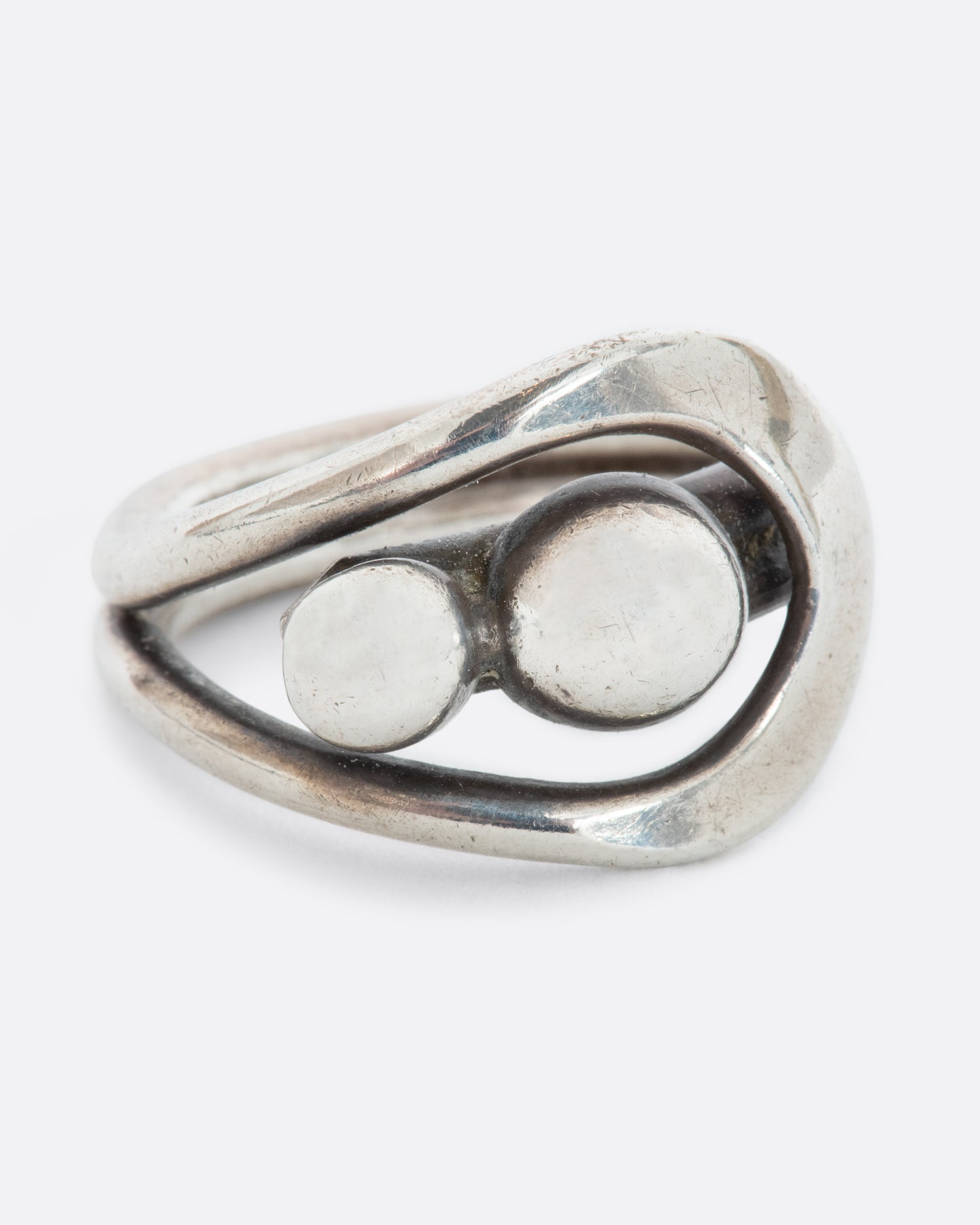 A sterling silver wrap ring with two spheres at the center. Shown from the front.