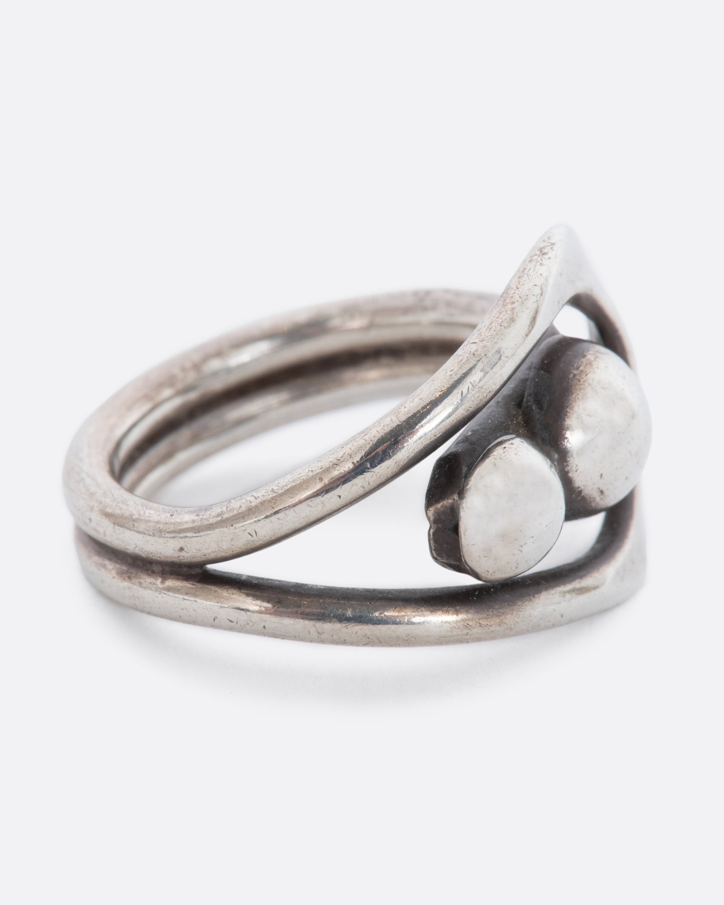 A sterling silver wrap ring with two spheres at the center. Shown from the side.