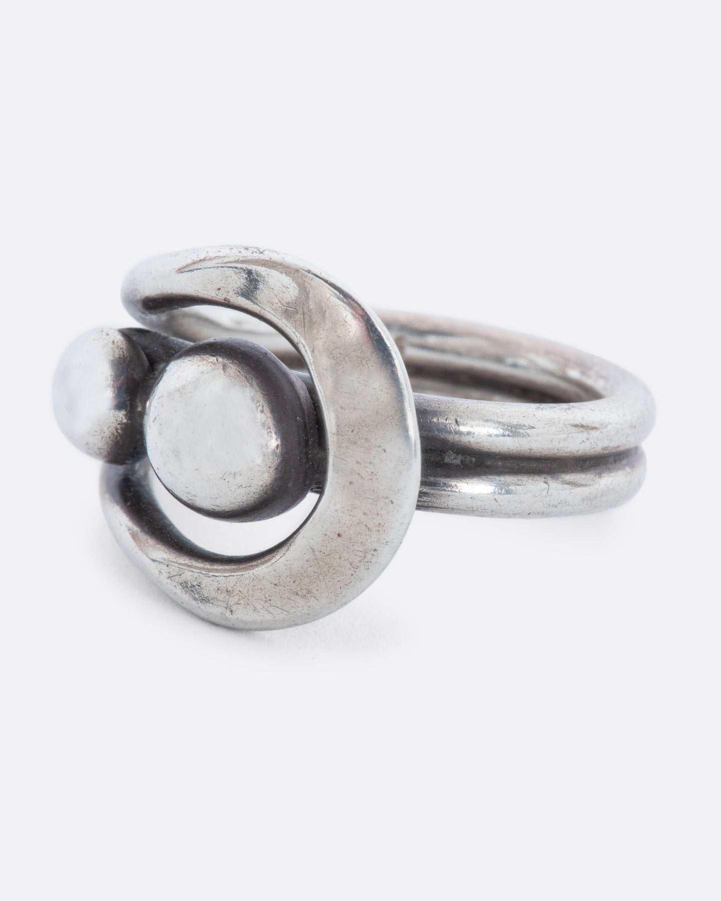 A sterling silver wrap ring with two spheres at the center. Shown from the side.