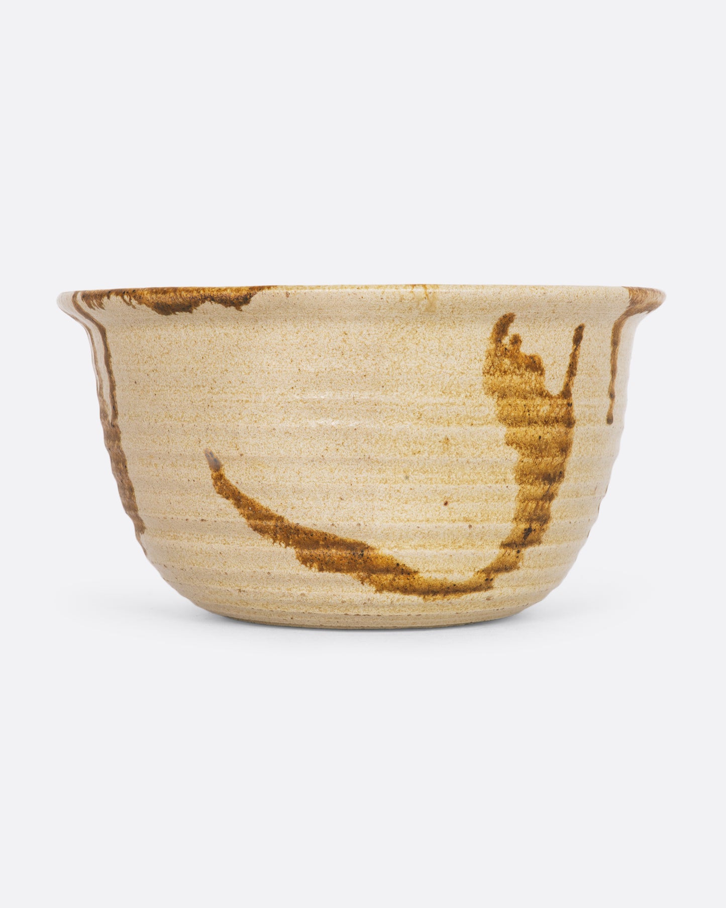 A beige ceramic bowl with brown splatter. View from the front.