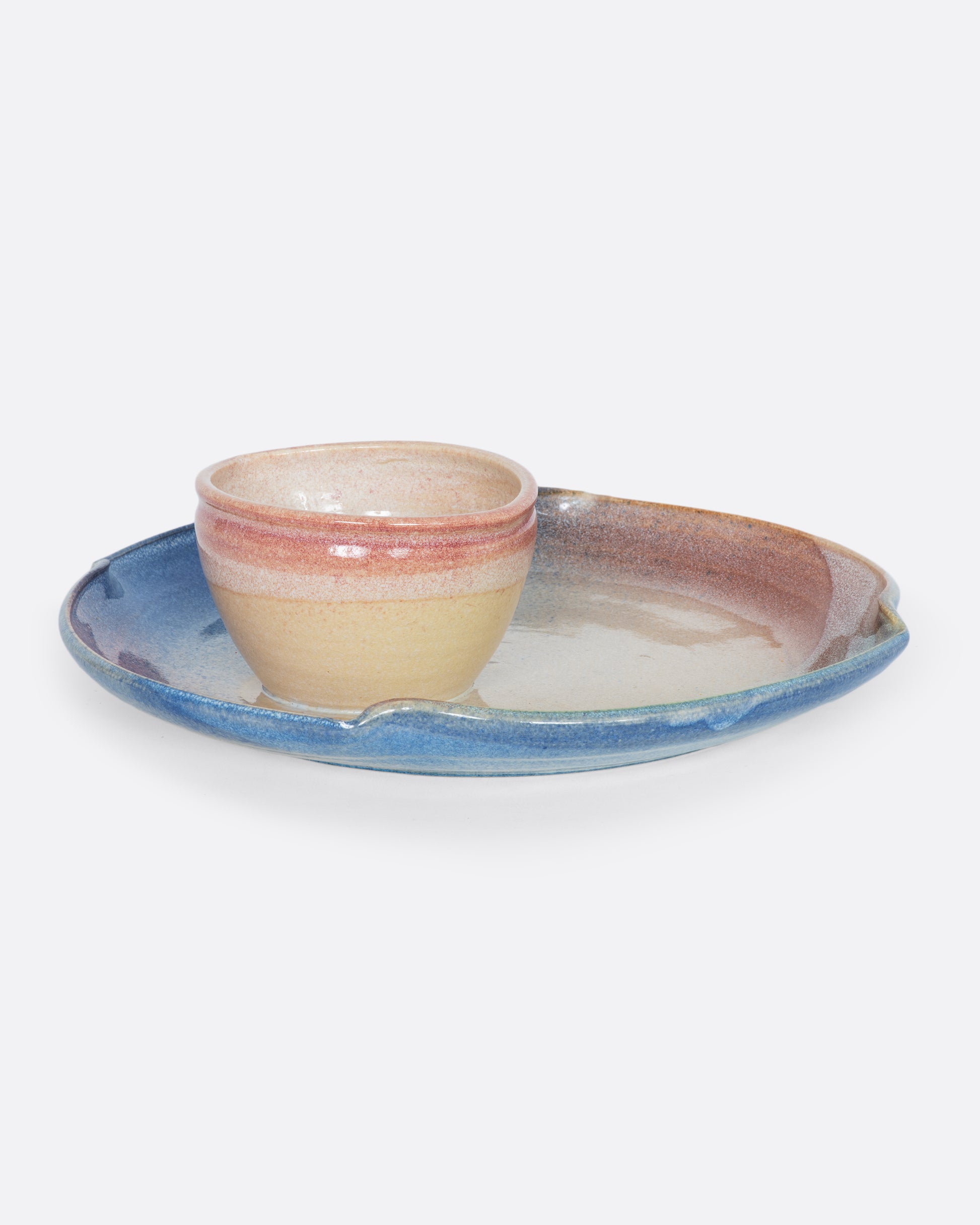 A ceramic chip and dip plate with a painted pink, blue, and green motif. Shown from the front.