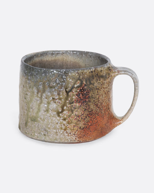 A brown and beige colored hand thrown ceramic mug. View from the side.