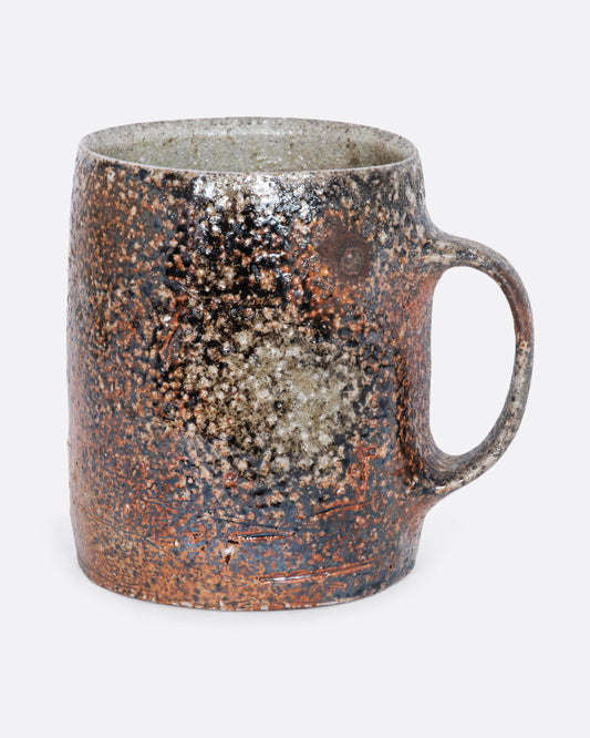 A hand thrown brown ceramic mug. View from the side.