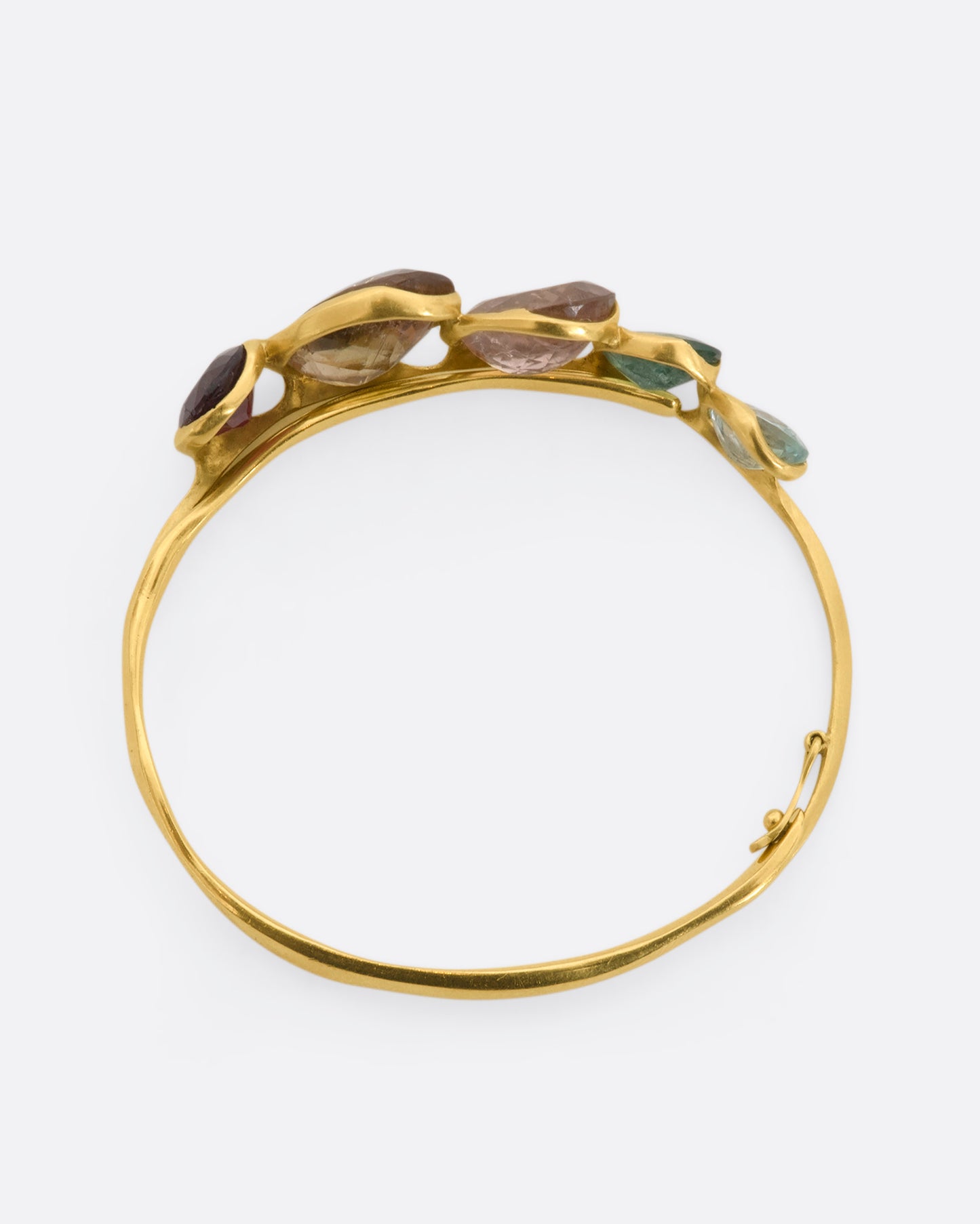 A yellow gold hinged bracelet crowned with five large different color tourmalines. View from above, closed.