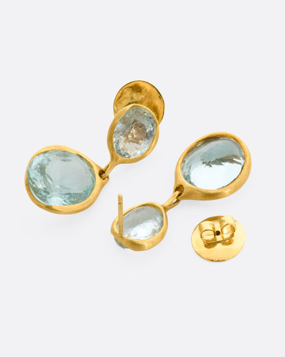 A pair of yellow gold aquamarine stud double drop  earrings. One earring is shown lying flat from the front, the other is shown open lying flat from the back.