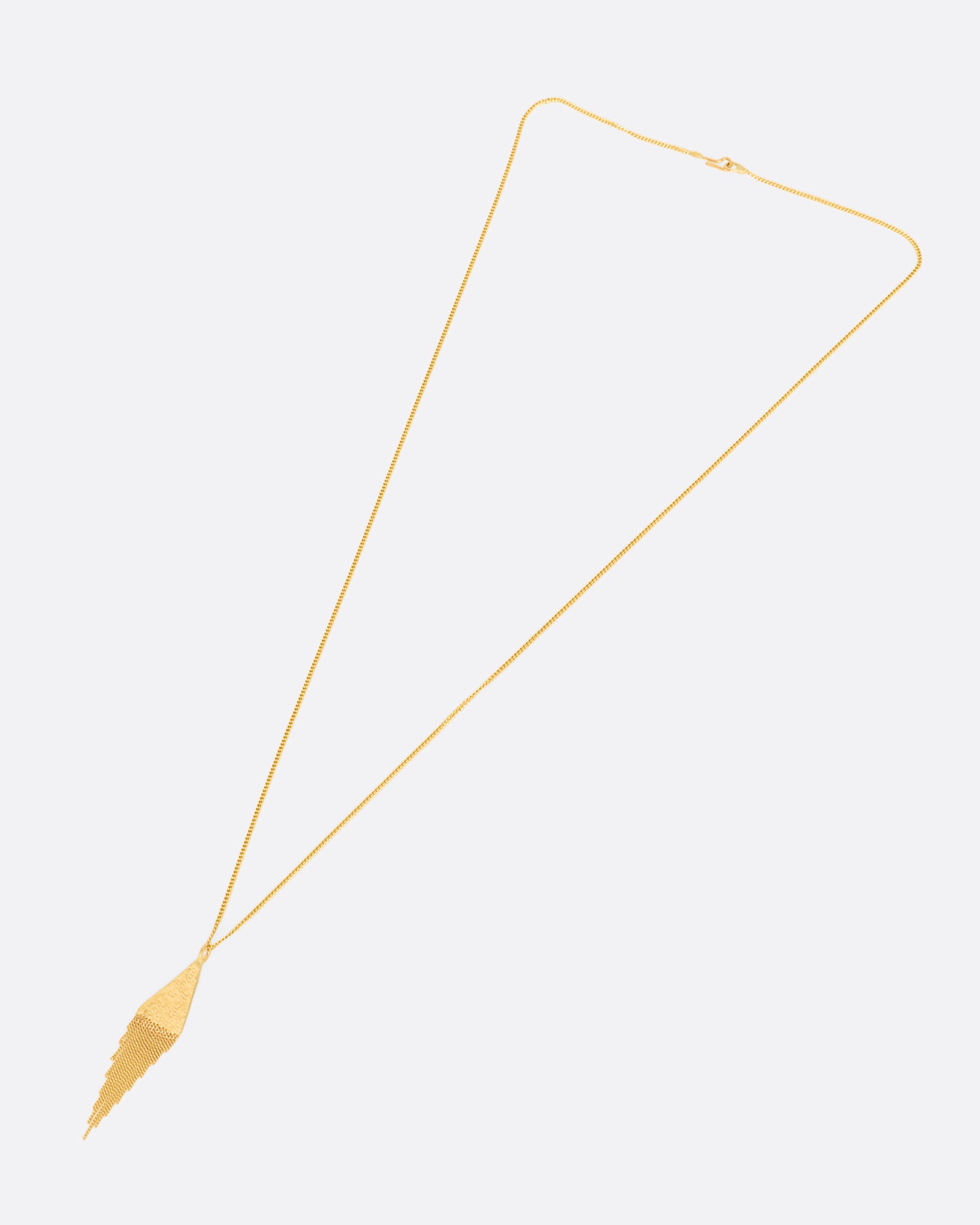 A yellow gold necklace with a fringed triangle pendant. View of the entire necklace laying flat.