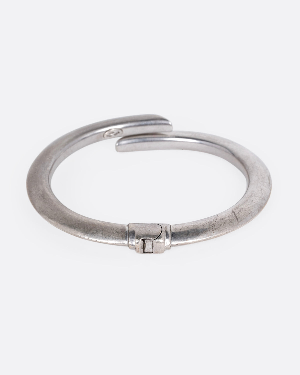A silver wrap bracelet with hinged back, shown from the back.