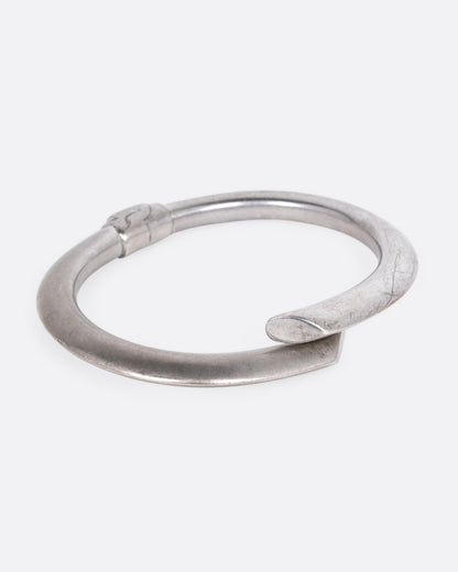 A silver wrap bracelet with hinged back, shown from the side.