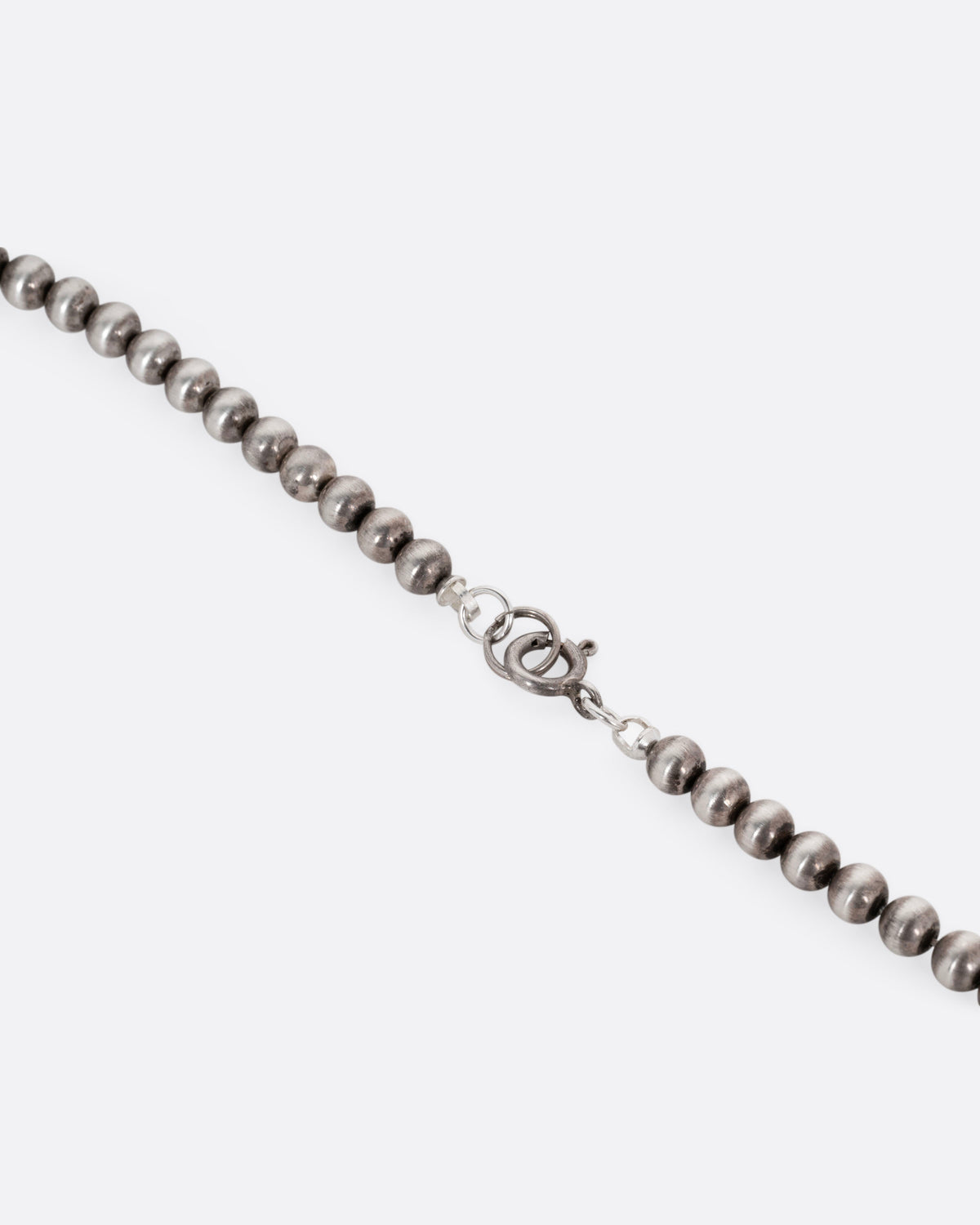 A close up of the clasp of a silver beaded necklace.