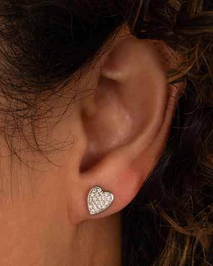 White gold pave diamond heart stud earrings worn on an ear
