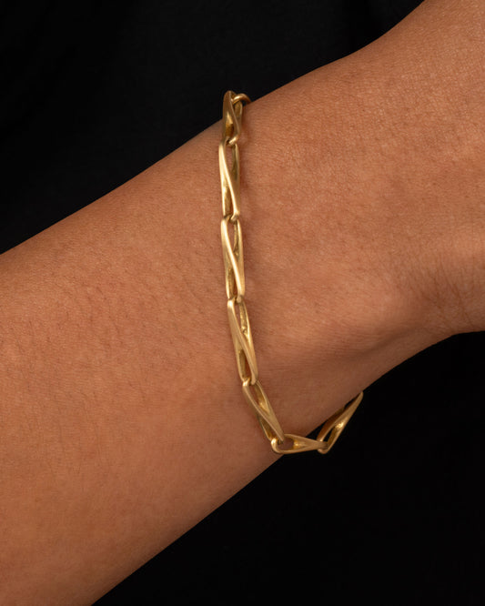 A close-up of a yellow gold chain bracelet worn on a person.