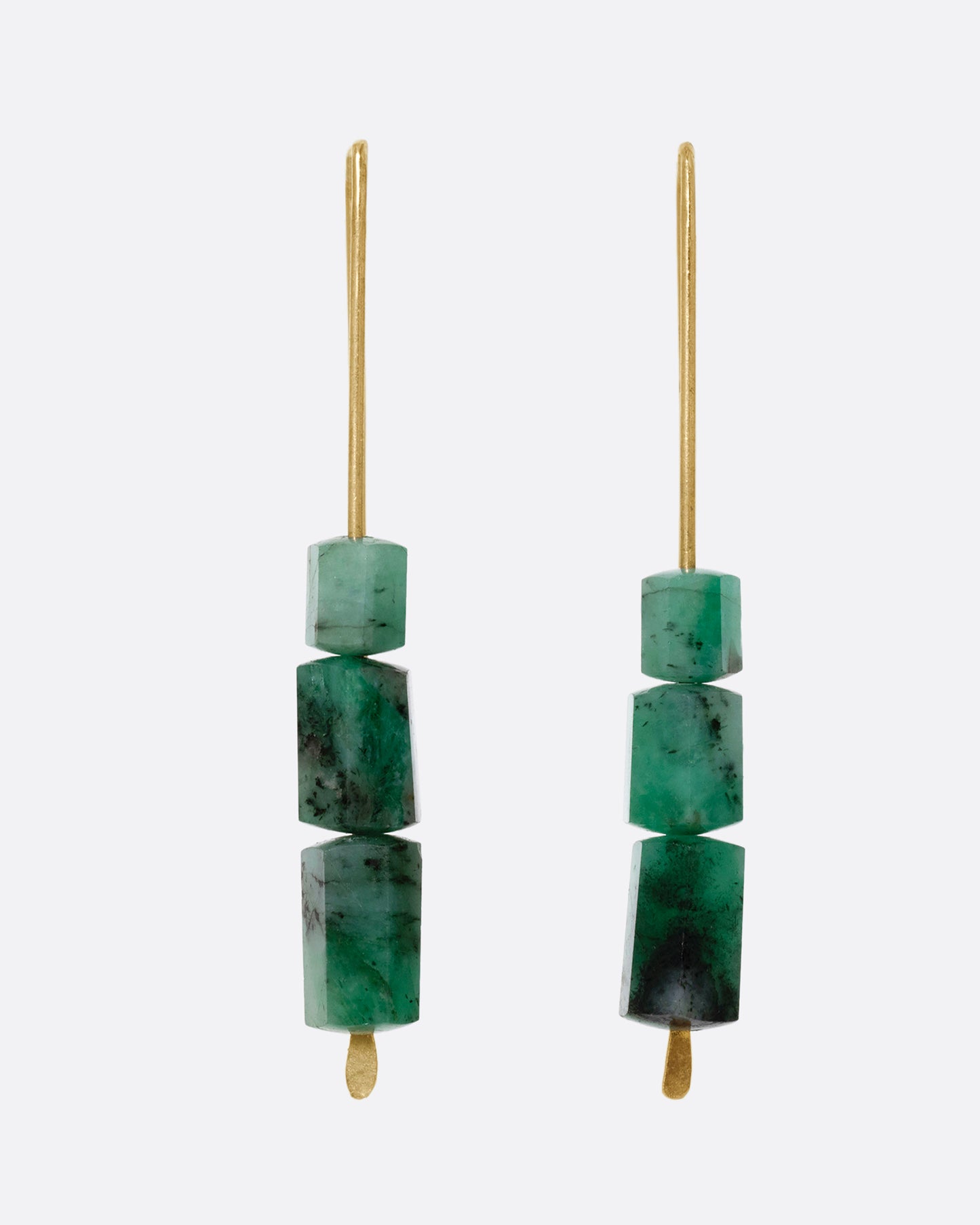 A pair of yellow gold hook earrings with three stacked freeform emeralds. Shown from the front.  