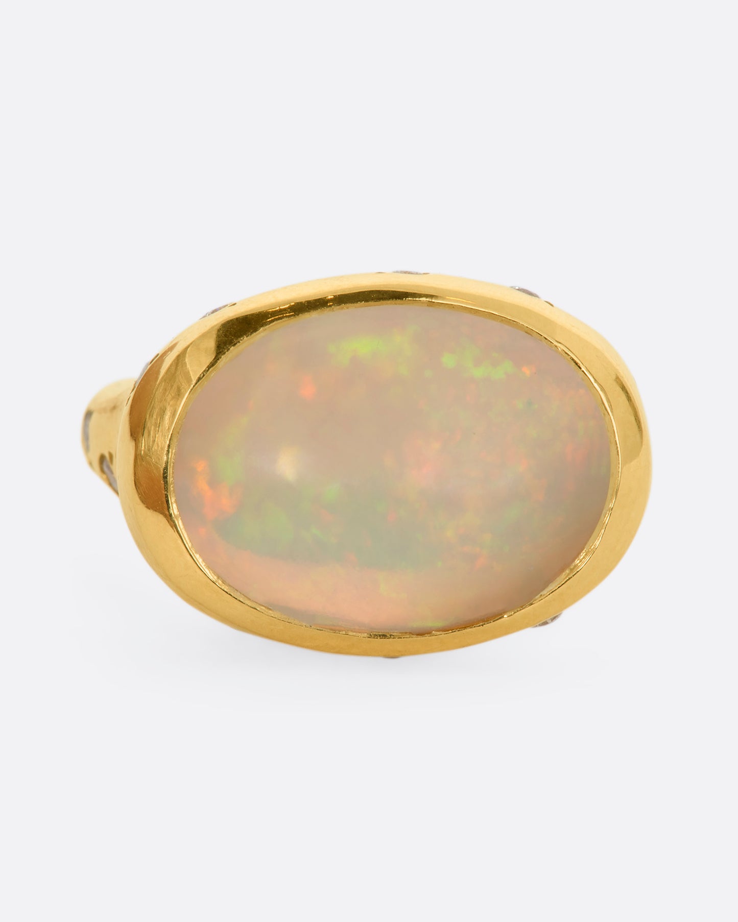 A polished yellow gold ring with a large east west oval Australian opal and diamonds on the setting and shoulders. View from the front.