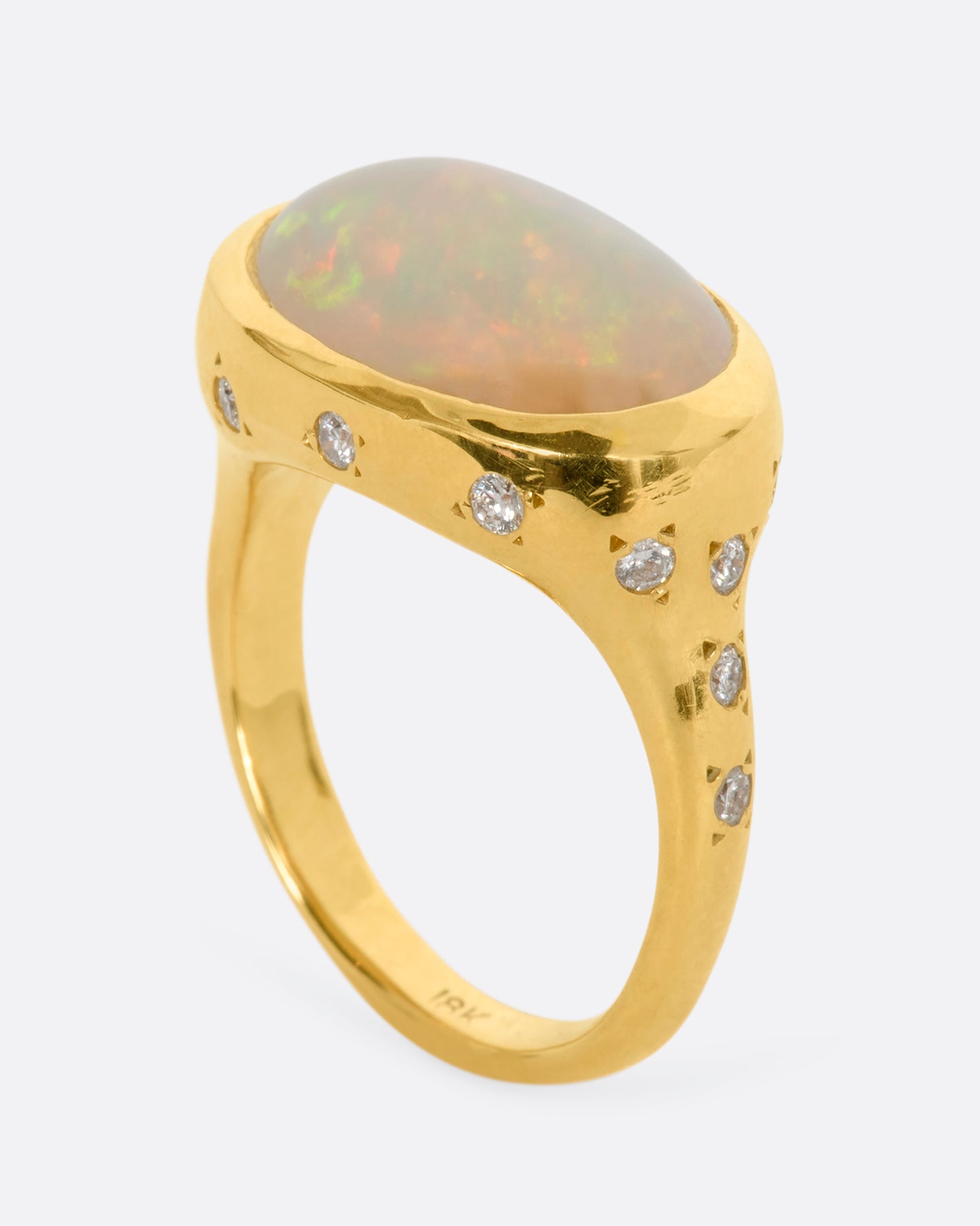 A polished yellow gold ring with a large east west oval Australian opal and diamonds on the setting and shoulders. View from the side standing.