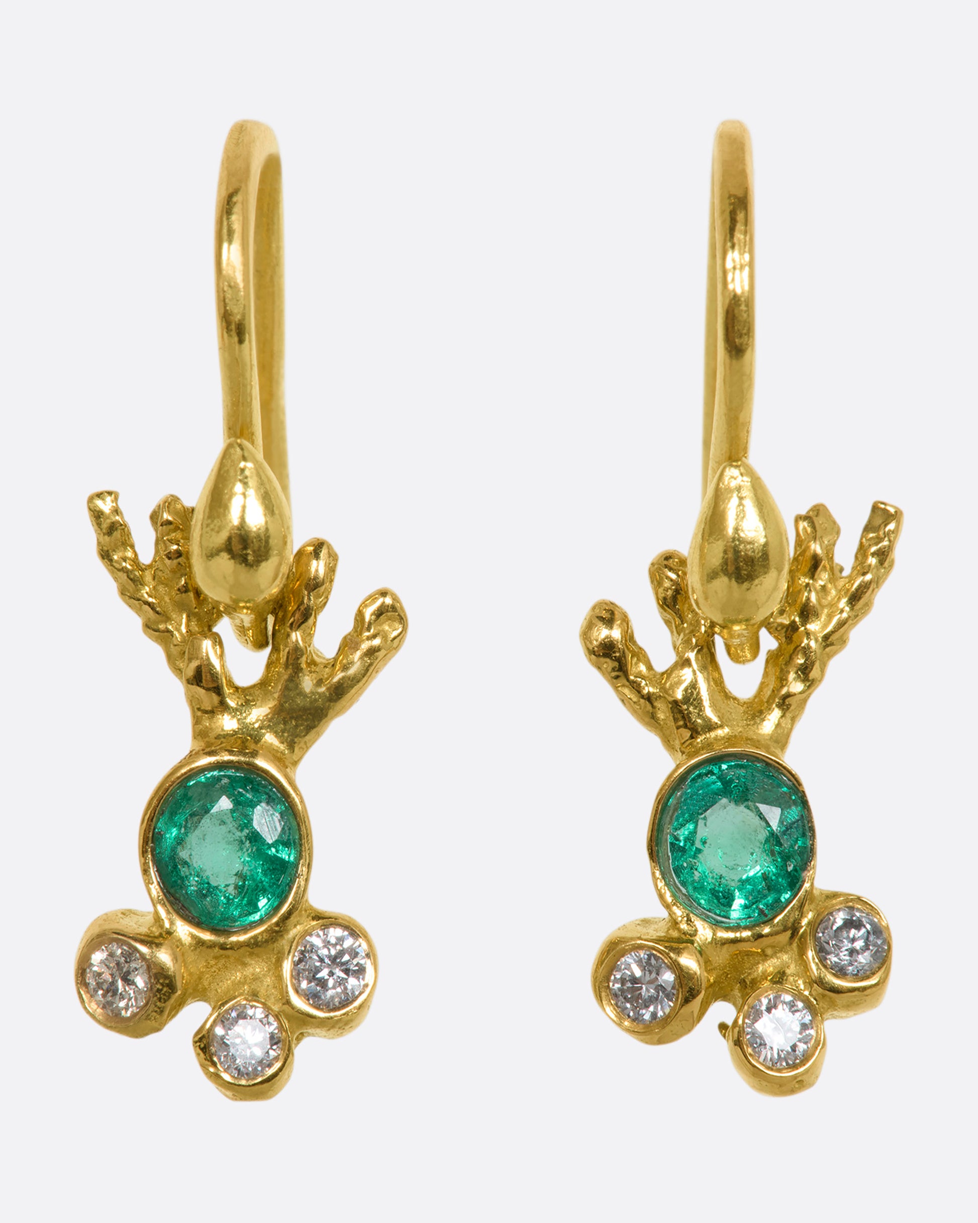 Yellow gold abstract ray earrings with an emerald at the center and three diamonds clustered below. View from the front.