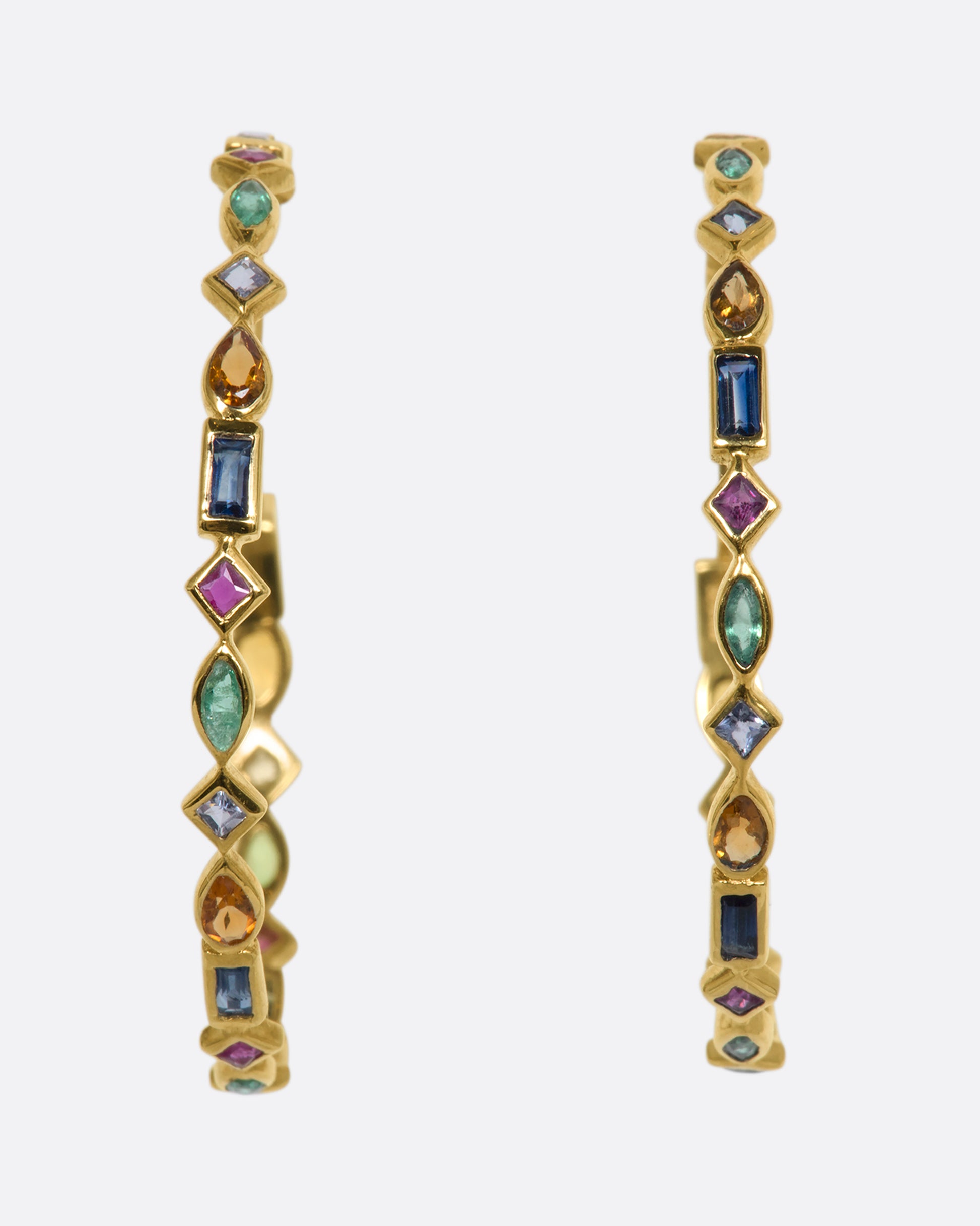 A yellow gold pair of earrings with mixed bezel set stones creating a hoop. View from the front.