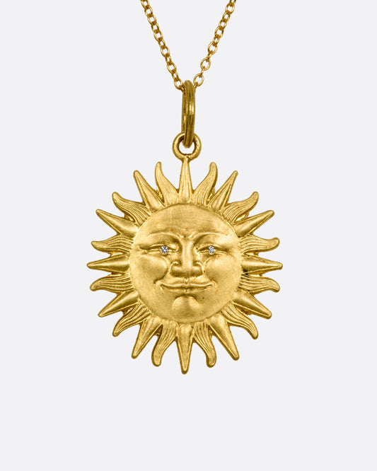 Yellow gold sun pendant with diamond eyes, view from the front. 