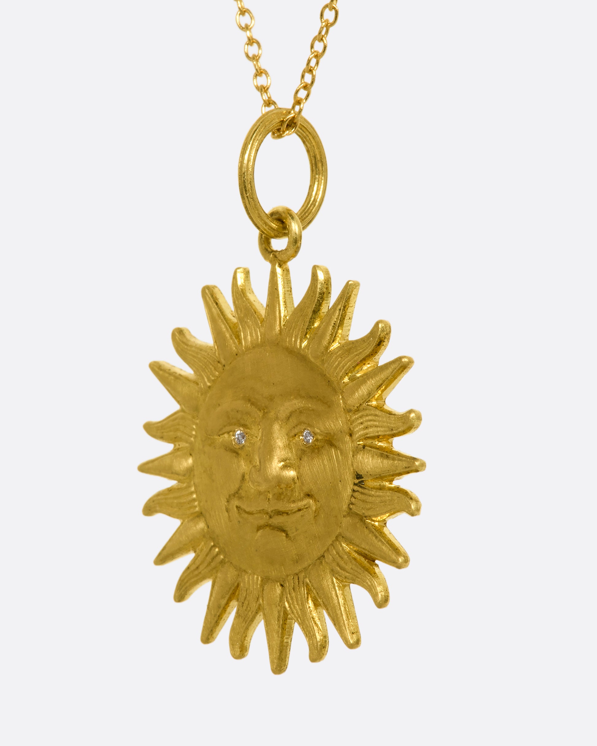 Yellow gold sun pendant with diamond eyes, view from the side.