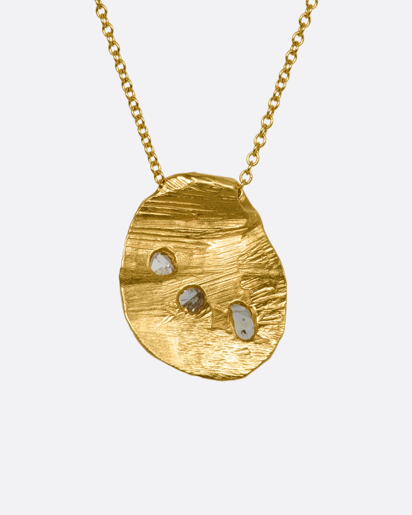 A heavy, hand carved, sliding gold pendant with three rose cut diamonds on a cable chain. View from the back.