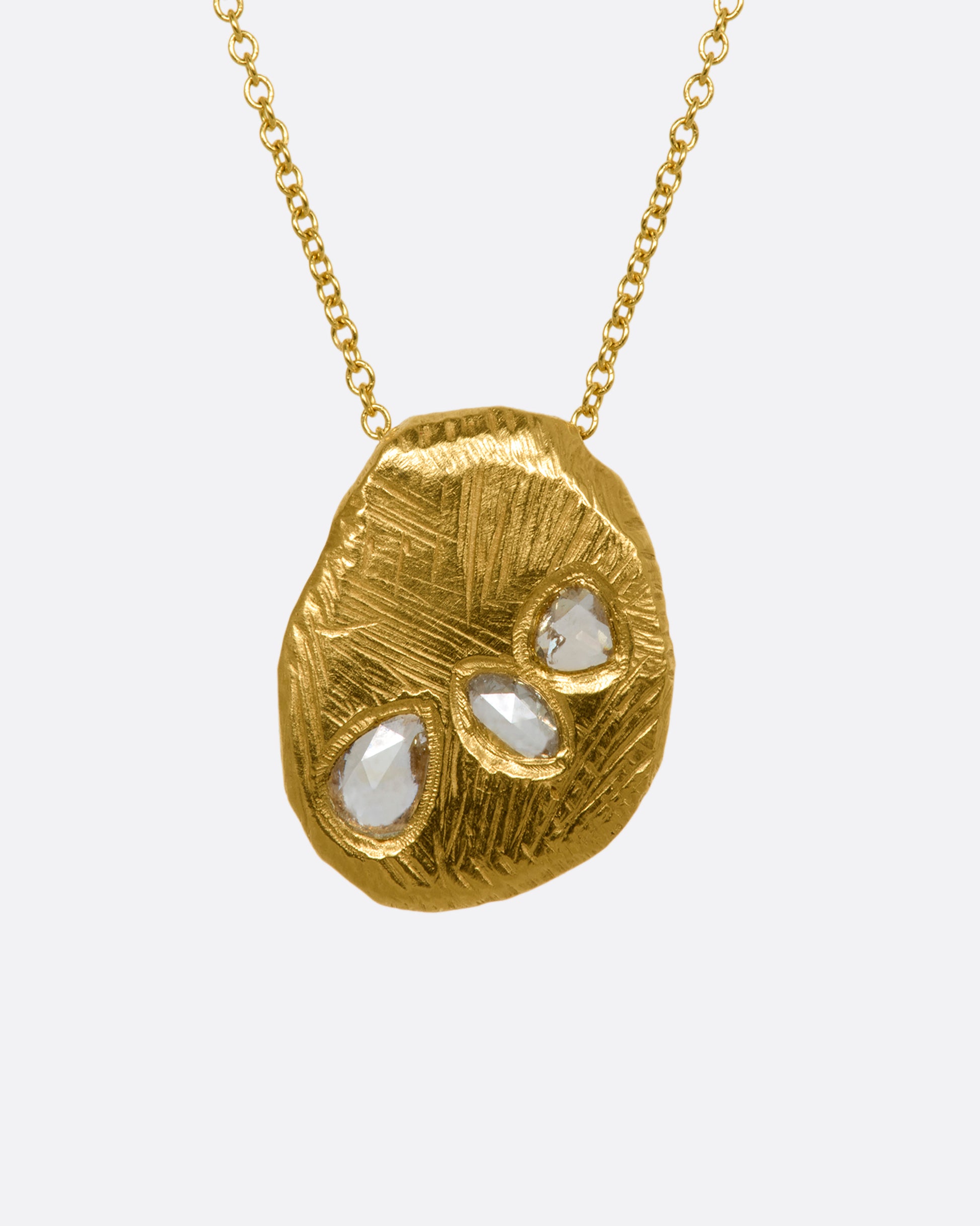 A heavy, hand carved, sliding gold pendant with three rose cut diamonds on a cable chain. View from the front.