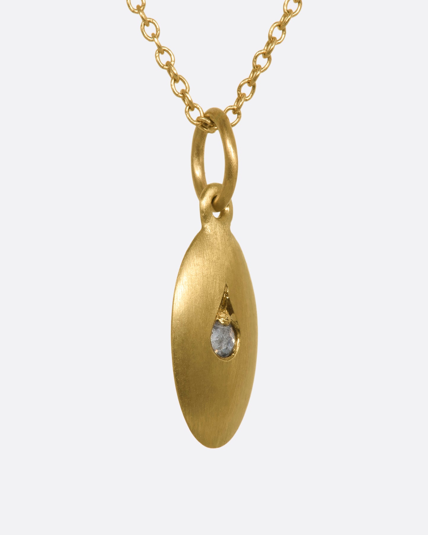 A yellow gold oval pendant with a diamond at the center. View from the side.