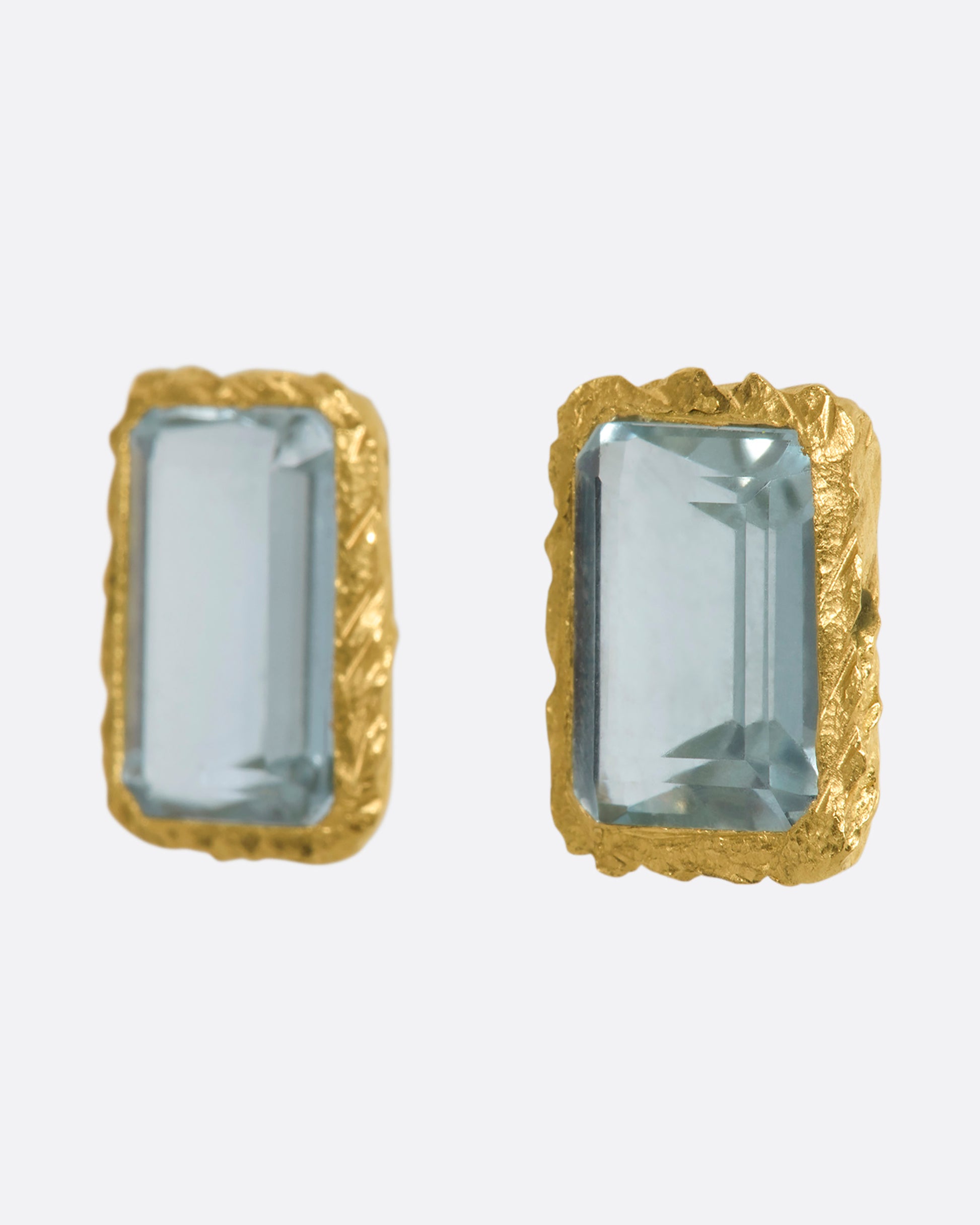 A yellow gold stud earrings with rectangular aquamarines. Shown from the side.