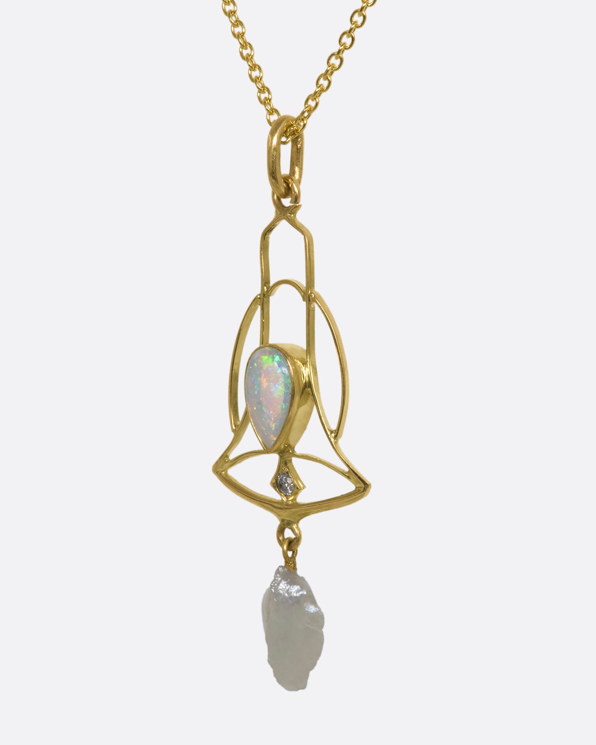 A yellow gold openwork bell pendant with an opal, diamond and dangling pearl. View from the side.