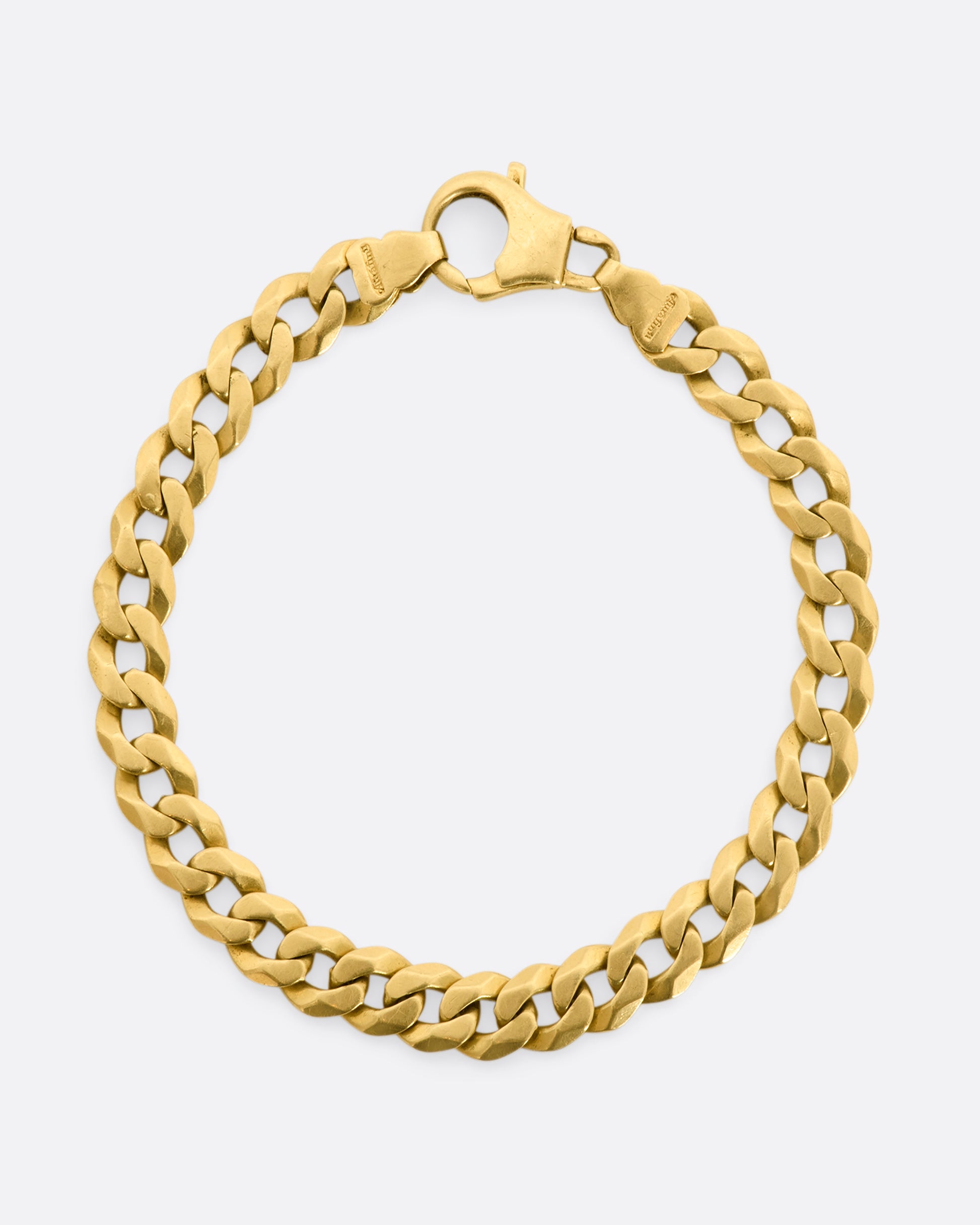 A yellow gold flat curb chain bracelet. View from above, laying flat and closed.