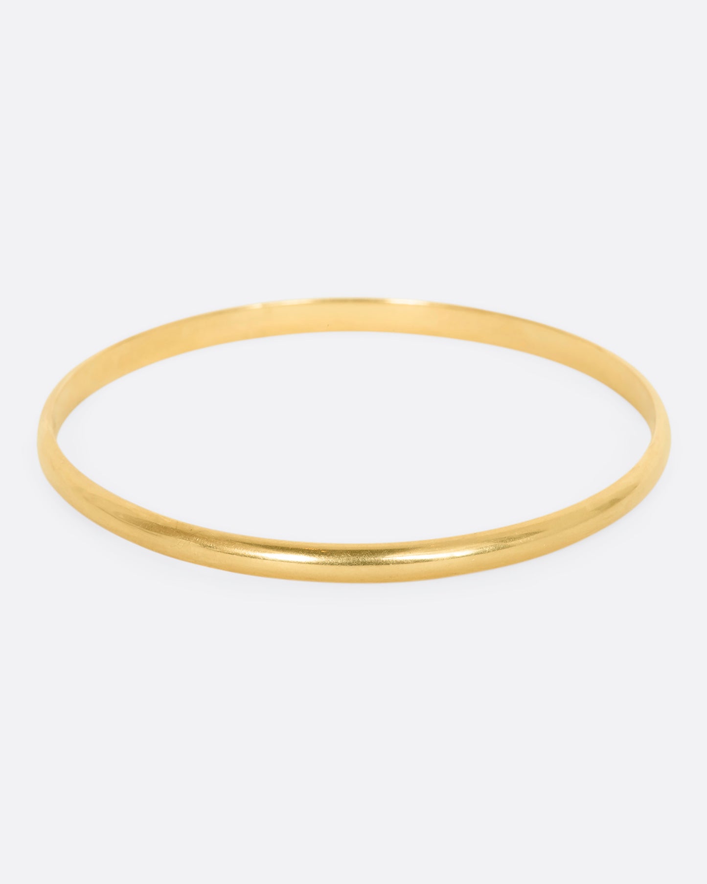 A yellow gold rounded bangle bracelet.