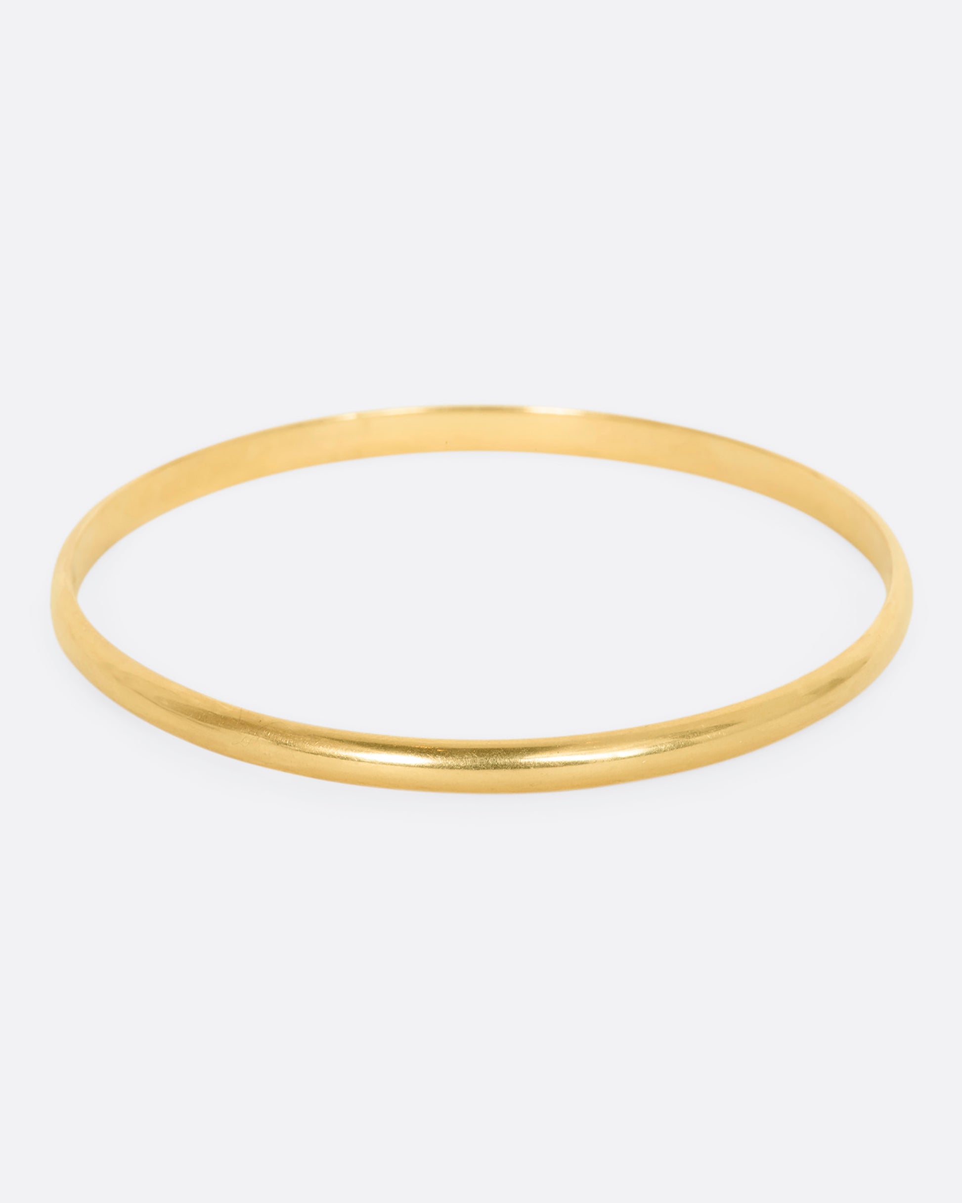 A yellow gold rounded bangle bracelet.