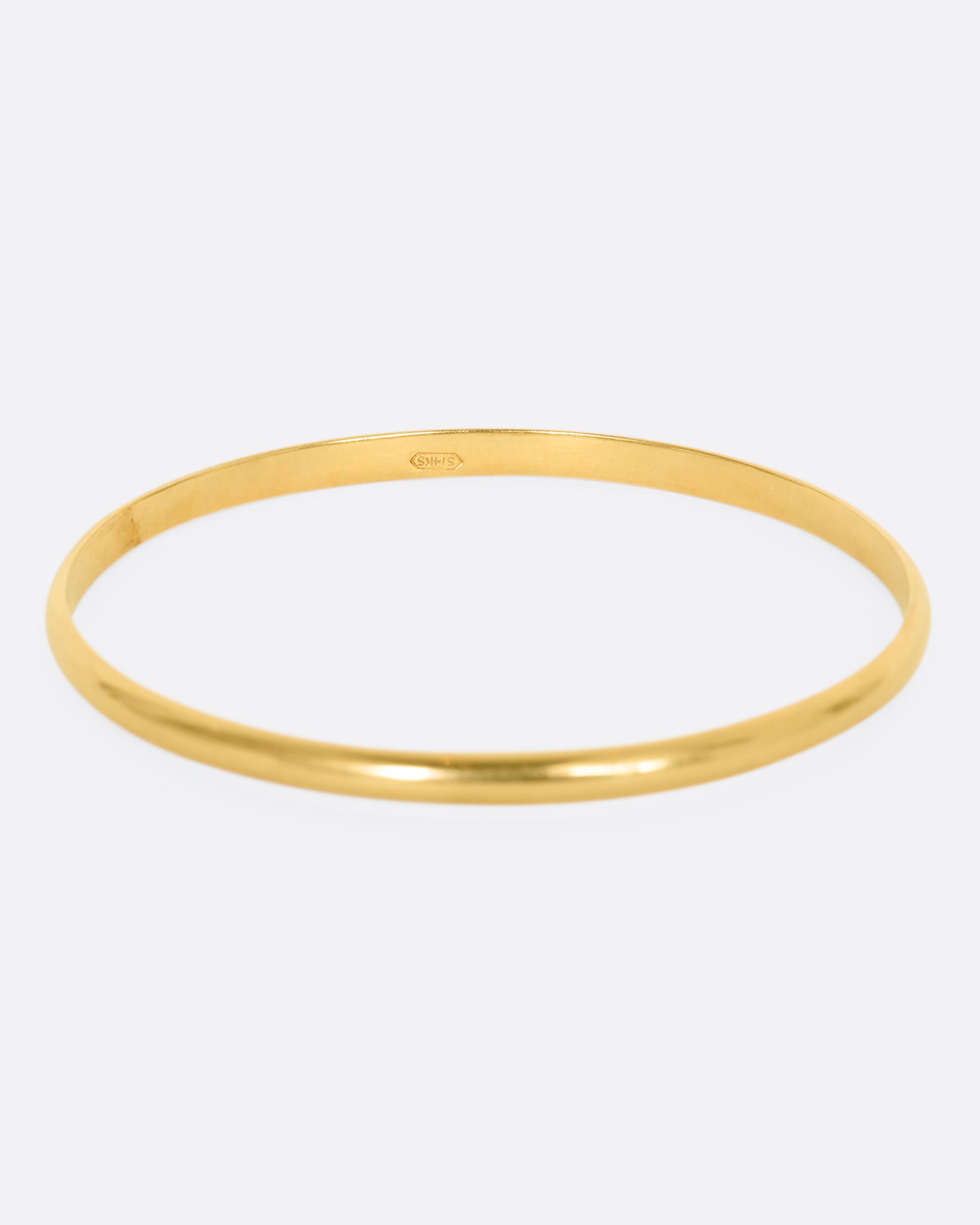 A yellow gold rounded bangle bracelet.