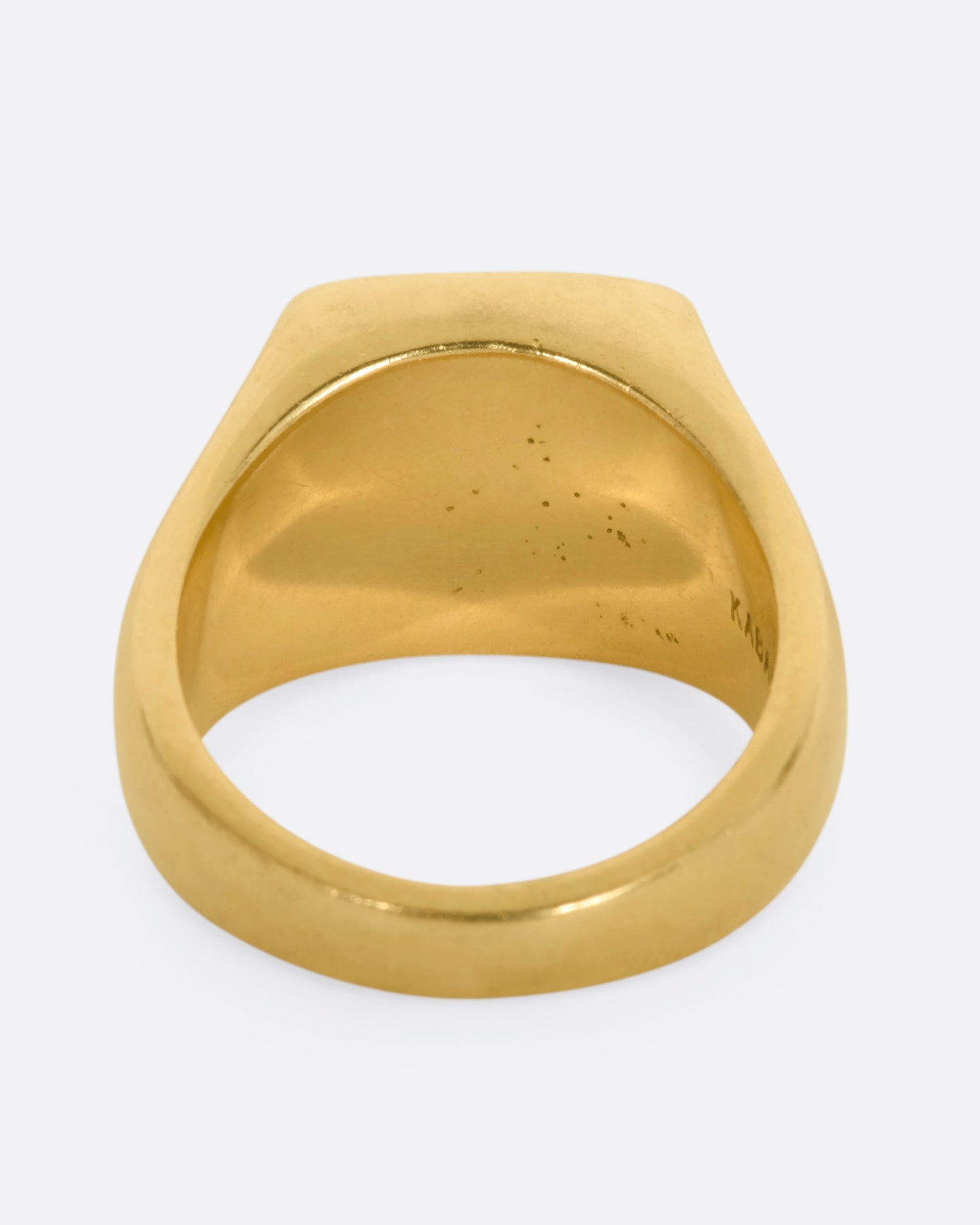 A yellow gold signet ring with onyx inlay and a princess cut diamond. View from the back.