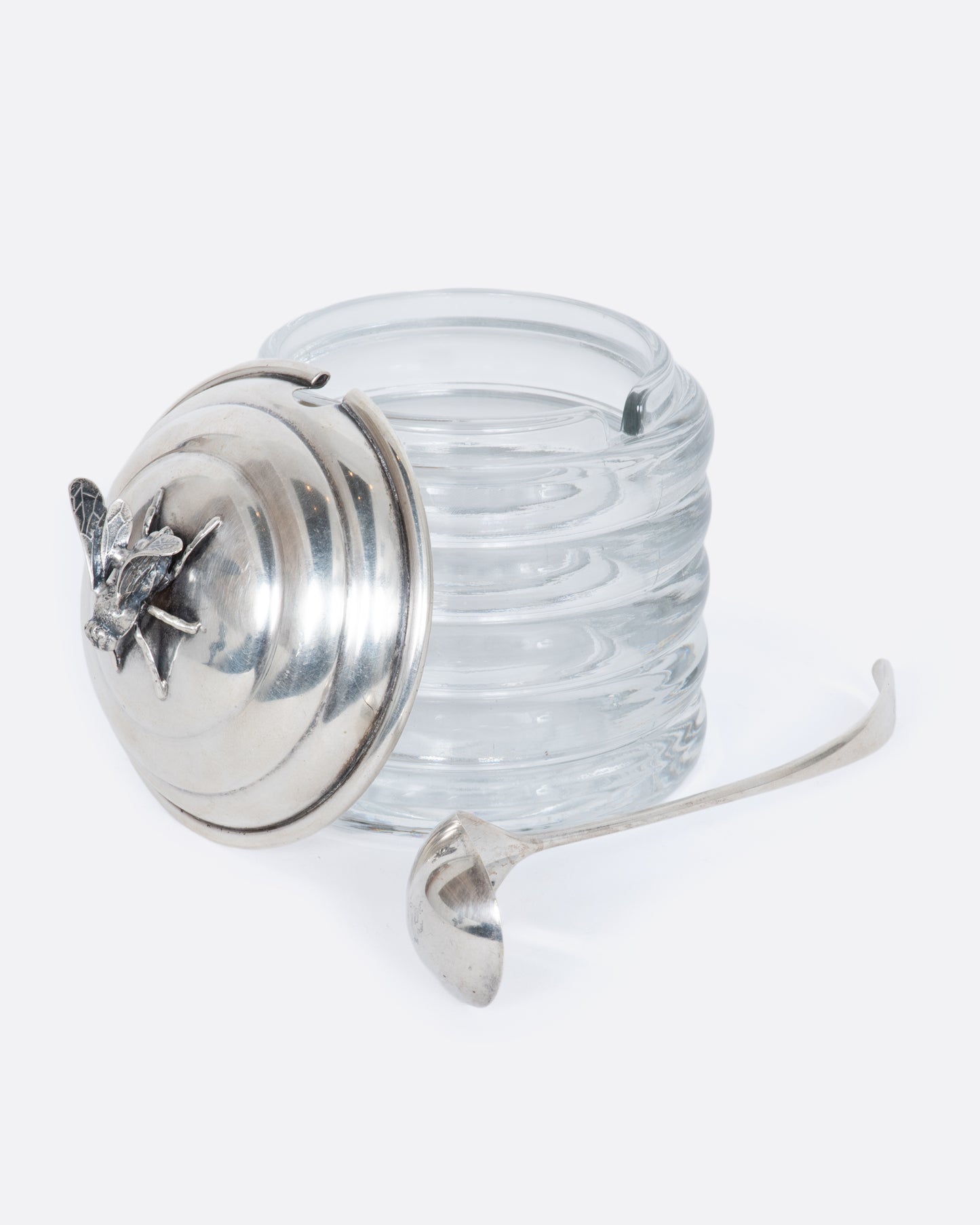 Glass honey pot with sterling lid and ladle featuring a fee on the lid.  View with the lid off.