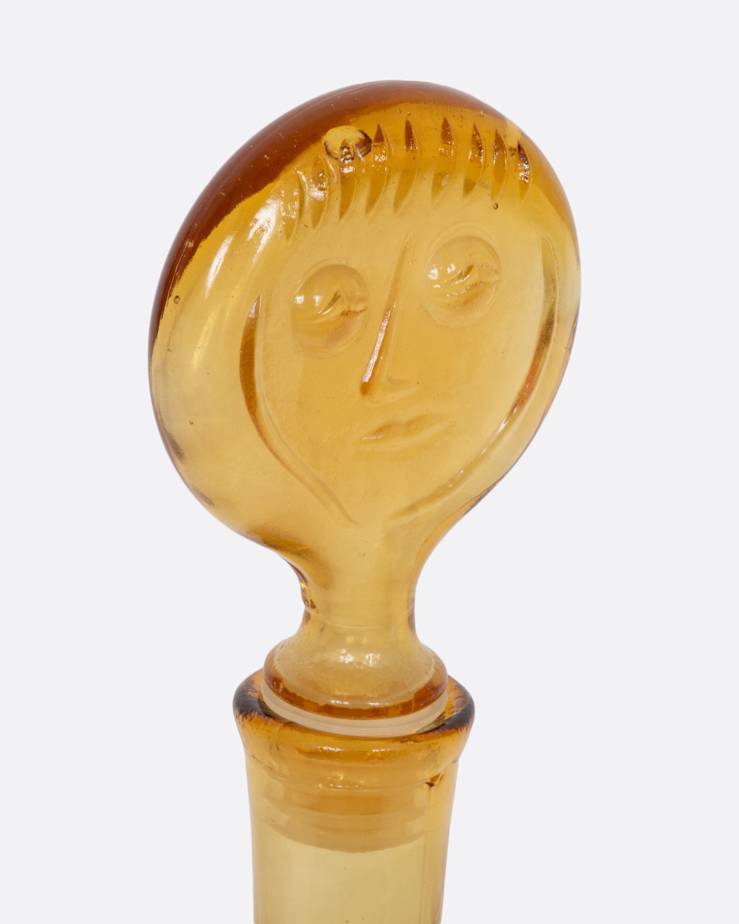 Clear yellow glass person decanter. View of the head close up.