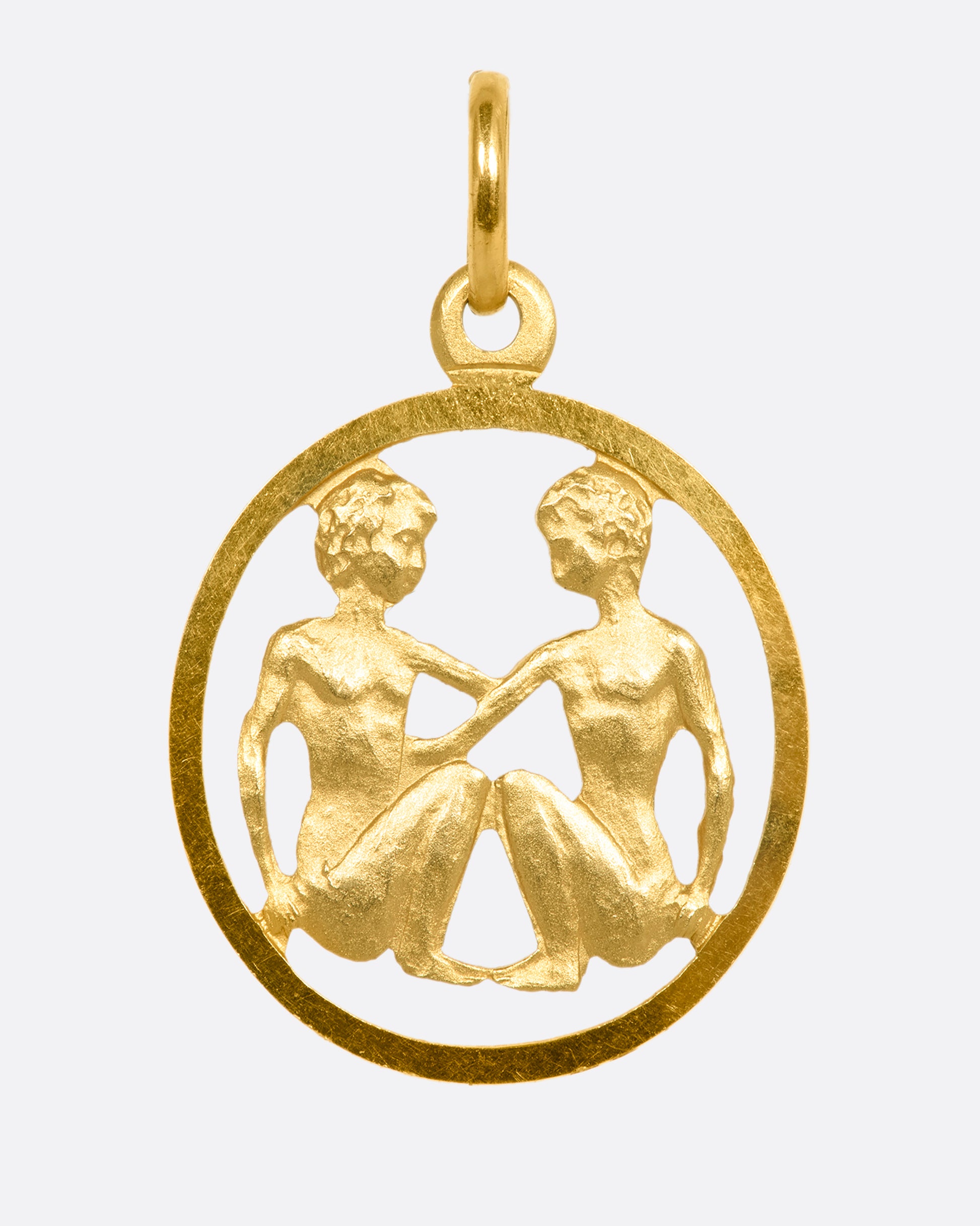 A yellow gold Gemini medallion charm or pendant. View from the front.