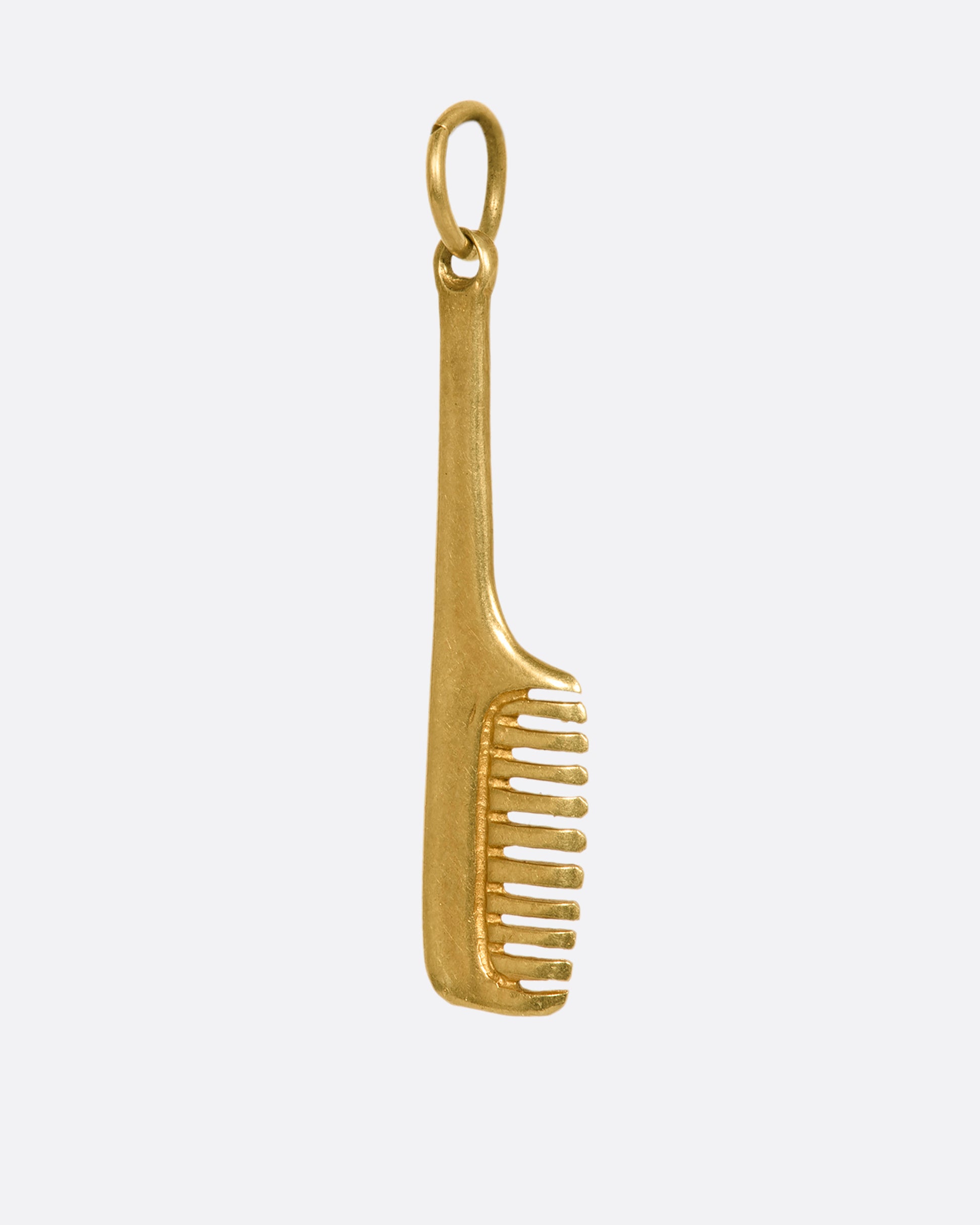 A yellow gold handled comb charm. View from the side.