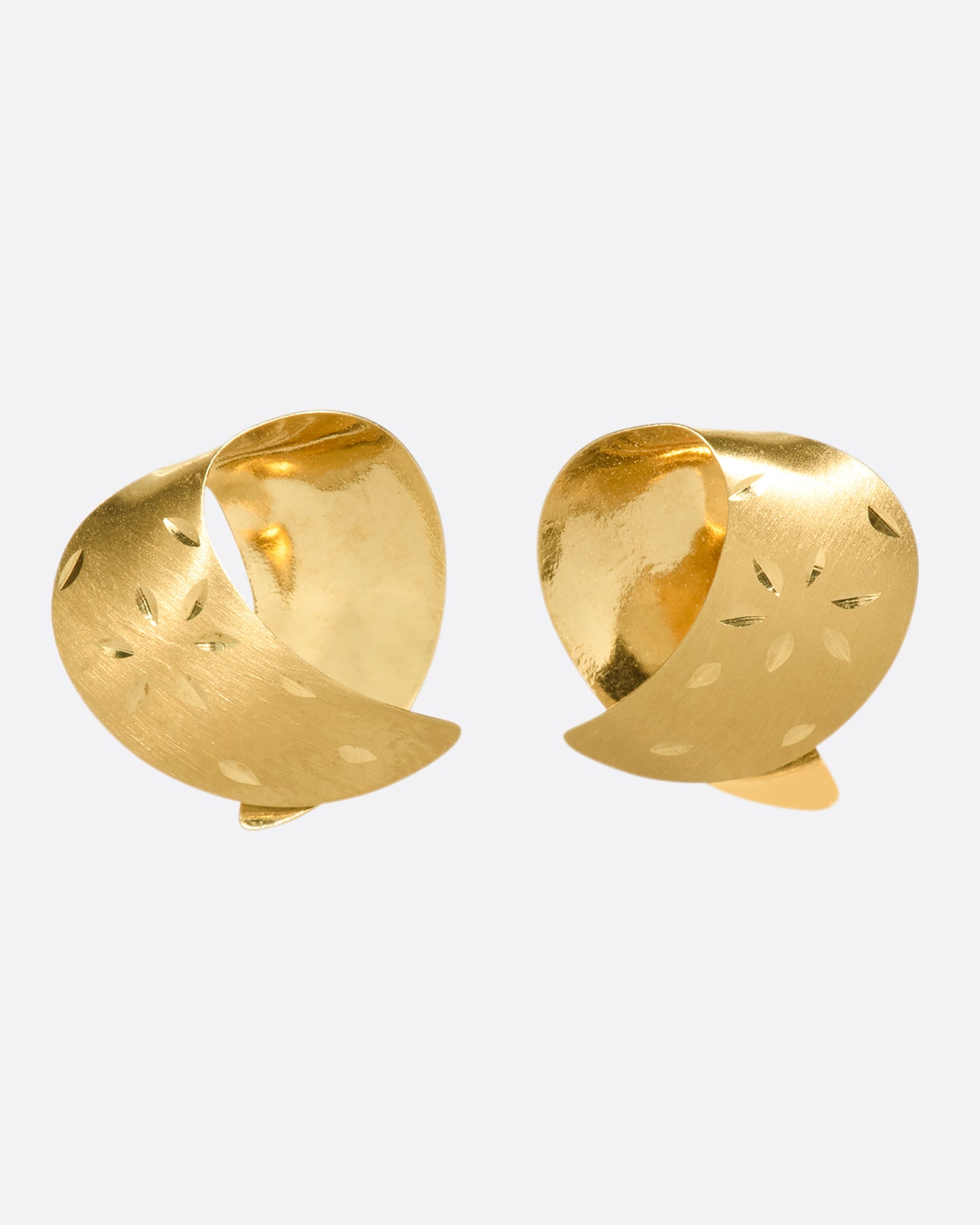 These vintage lightweight, folded studs are made of both matte and polished 14K gold. They're engraved with floral details that pick up light as you move.