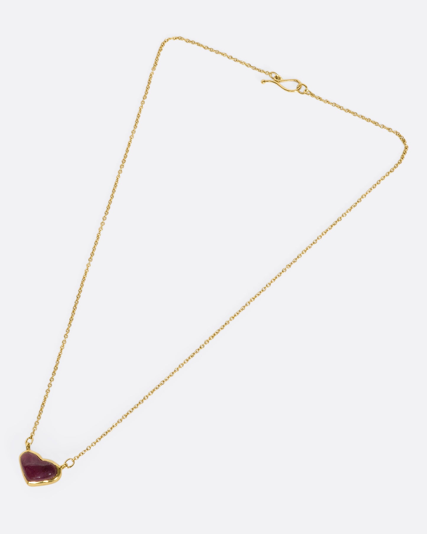 This 18k gold chain holds a unique watermelon rubellite heart encased in a gold bezel setting