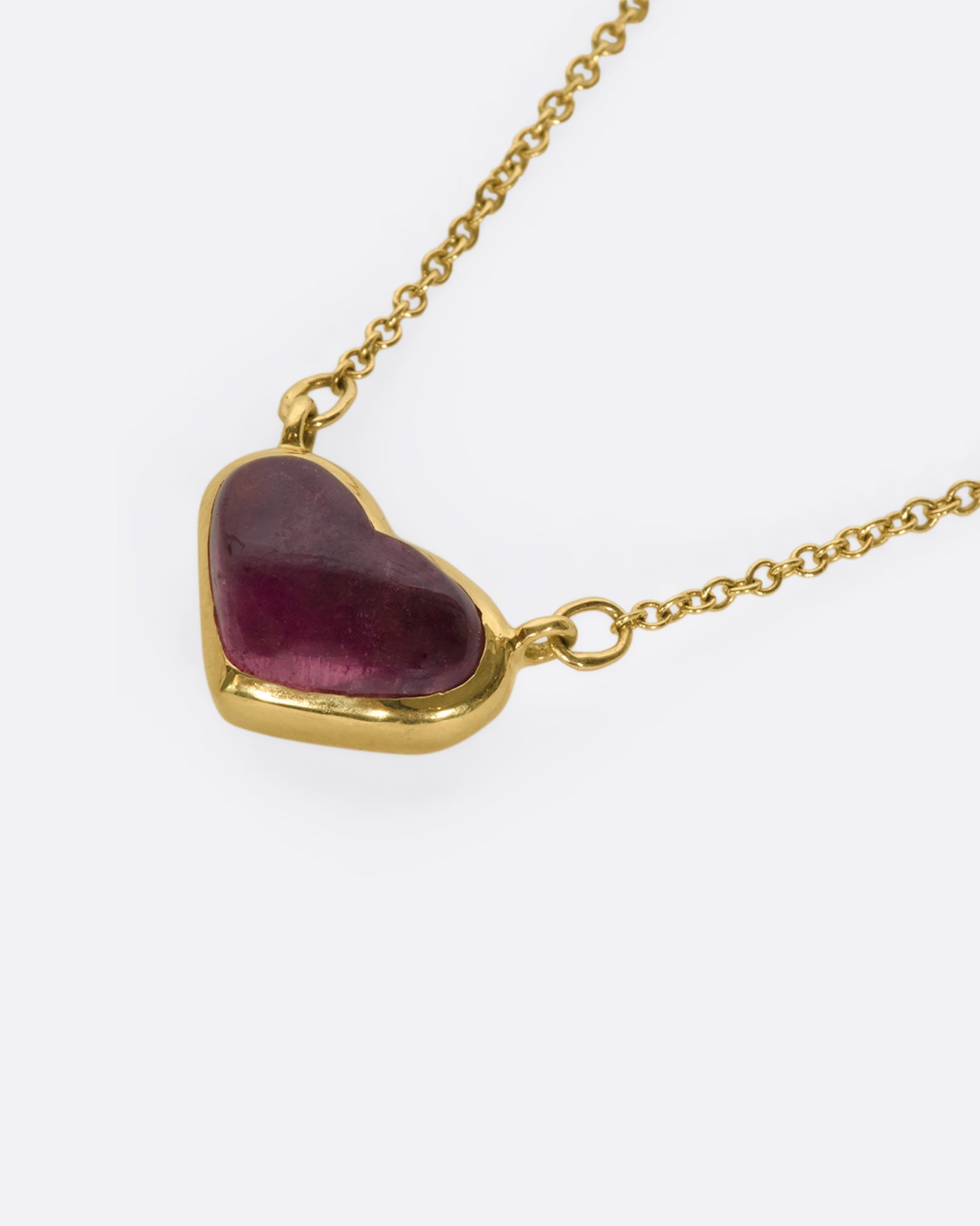 This 18k gold chain holds a unique watermelon rubellite heart encased in a gold bezel setting