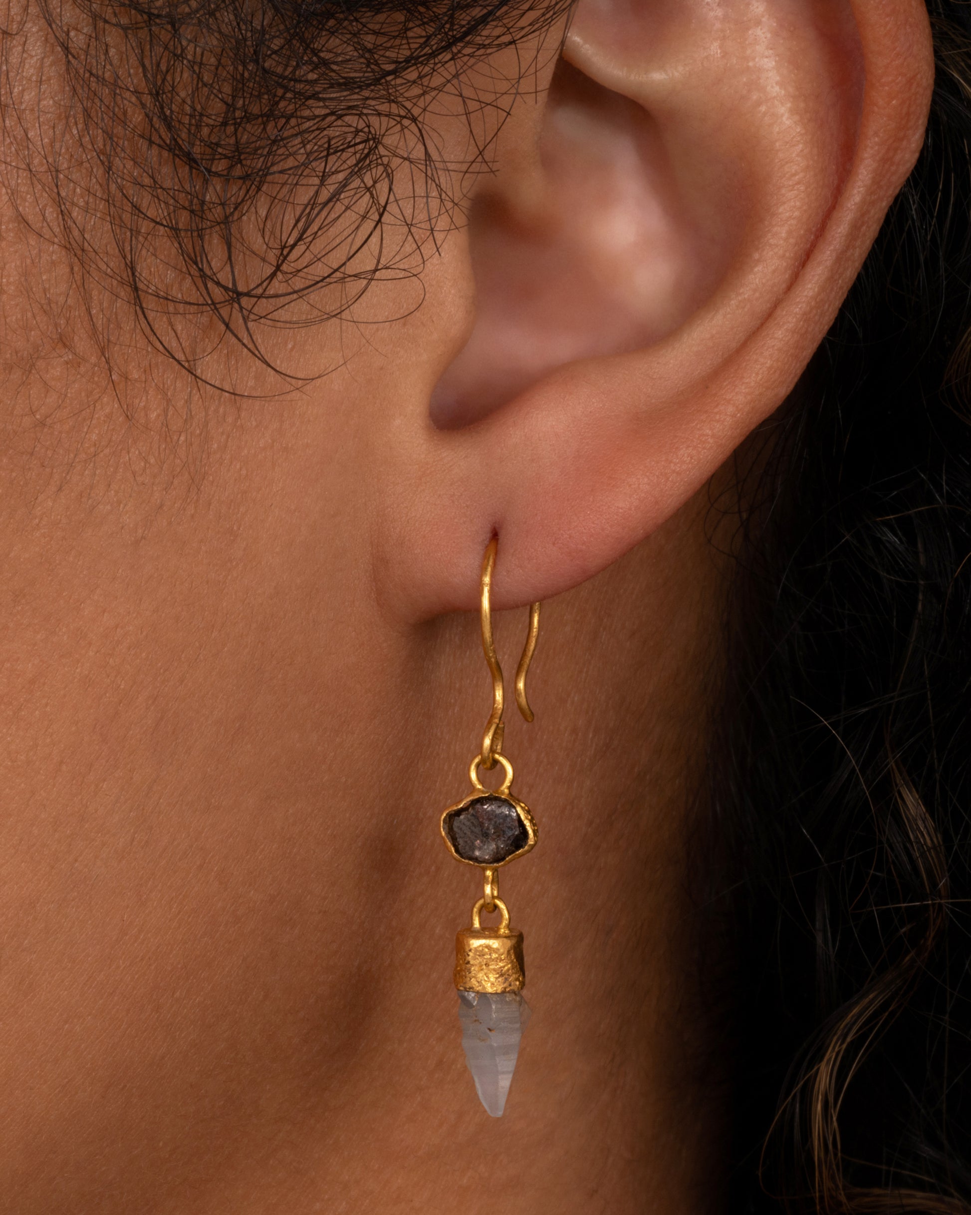 A yellow gold drop earring with a Borneo diamond and a Sri Lanken sapphire, shown on a person.