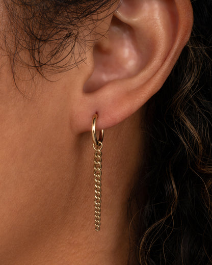 Metier graduated chain dangle in yellow gold worn on a hoop in an ear, a short chain with links getting larger toward the bottom