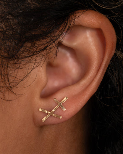 Christine Fail Chaos stud earring in Fairmined gold worn on an ear, short hammered gold bars crossing at random angles