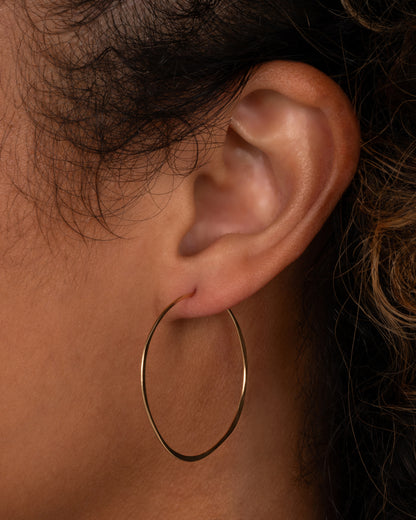 Christine Fail medium round hoop earring in Fairmined gold worn on an ear, a thin hand-hammered wire circle